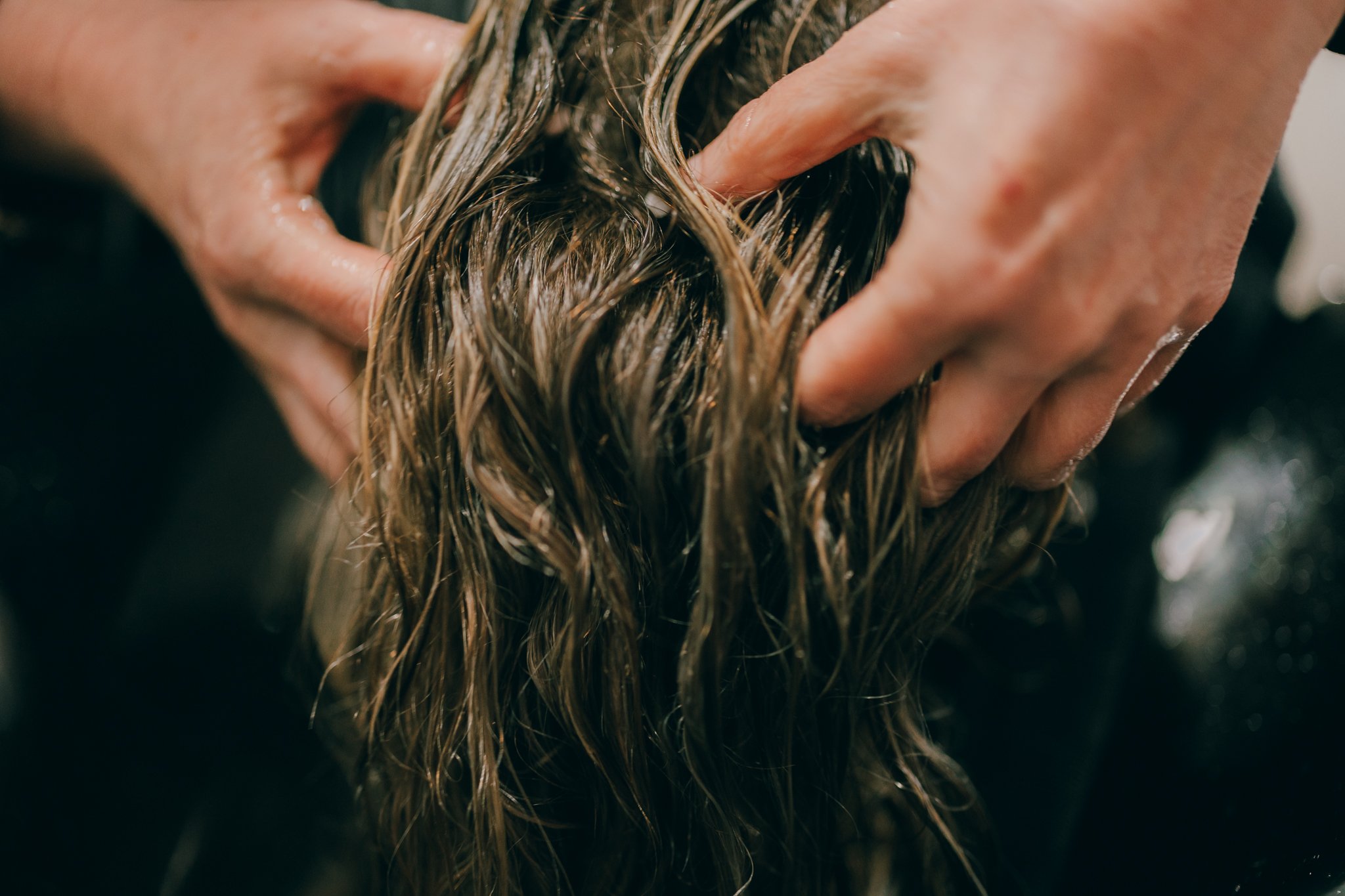 Hands massaging wet hair, possibly during a hair wash.