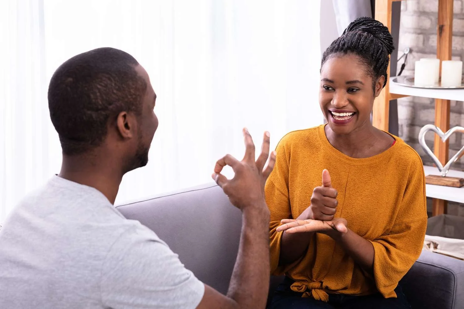 A man and woman engaged in a lively conversation, with the woman smiling and giving a thumbs up.