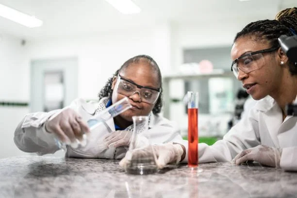 Two girls in a science lab conducting an experiment with test tubes and a beaker.