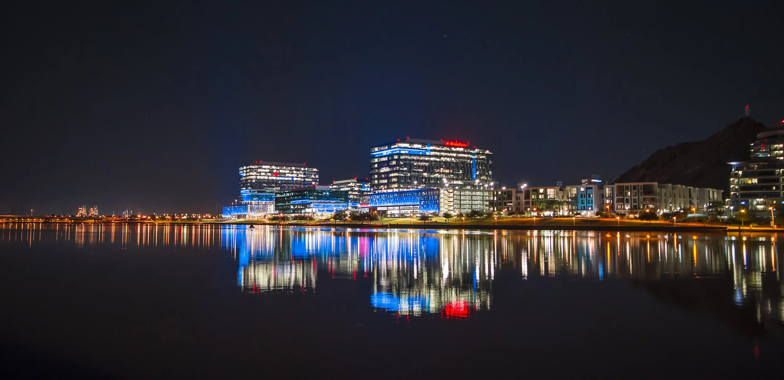 Night view of Tempe, Arizona skyline with illuminated buildings reflecting on Tempe Town Lake.