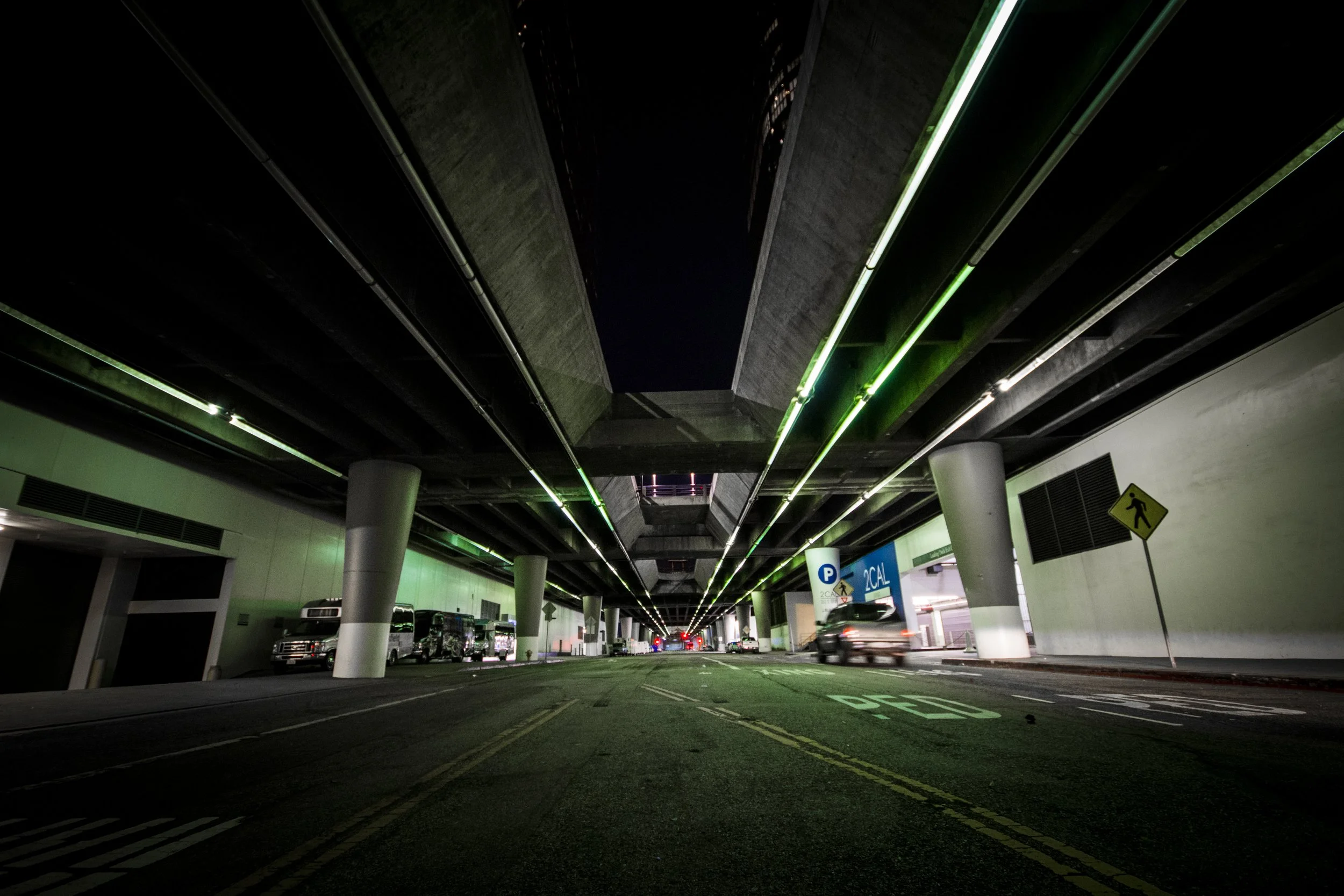 Underground parking garage at night with overhead lights and parked cars