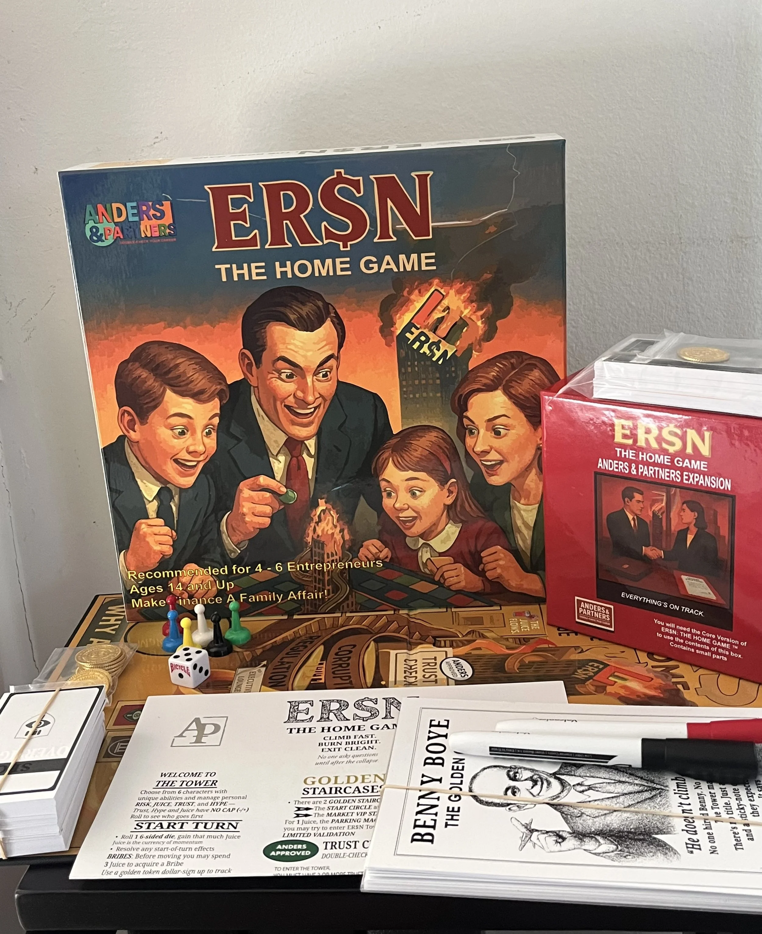 Board game titled 'ERŞN THE HOME GAME' featuring a family excitedly playing, with game components, coins, and a box of expansion pack nearby.