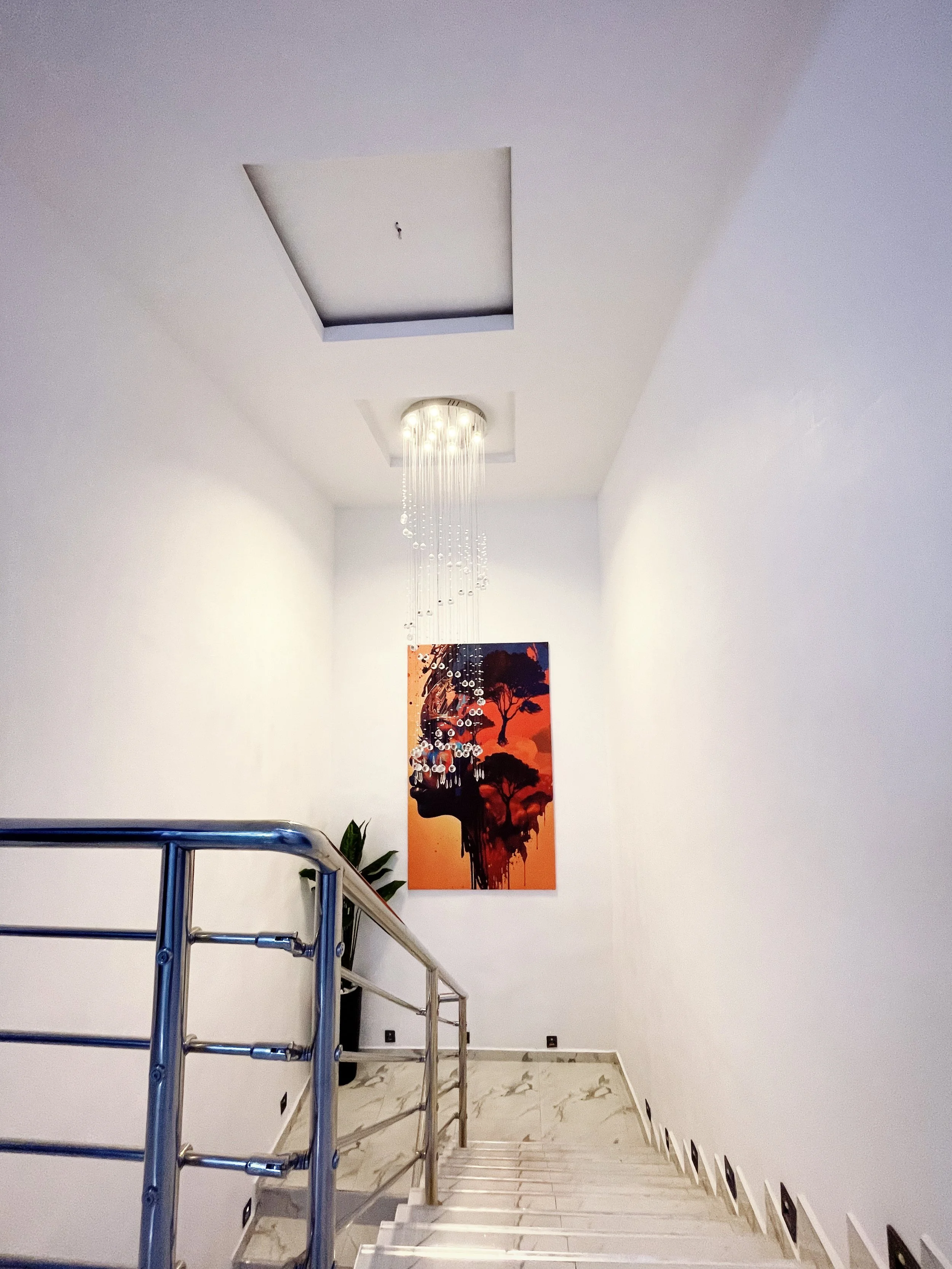 Interior stairway with modern chandelier, abstract art, and stainless steel railing