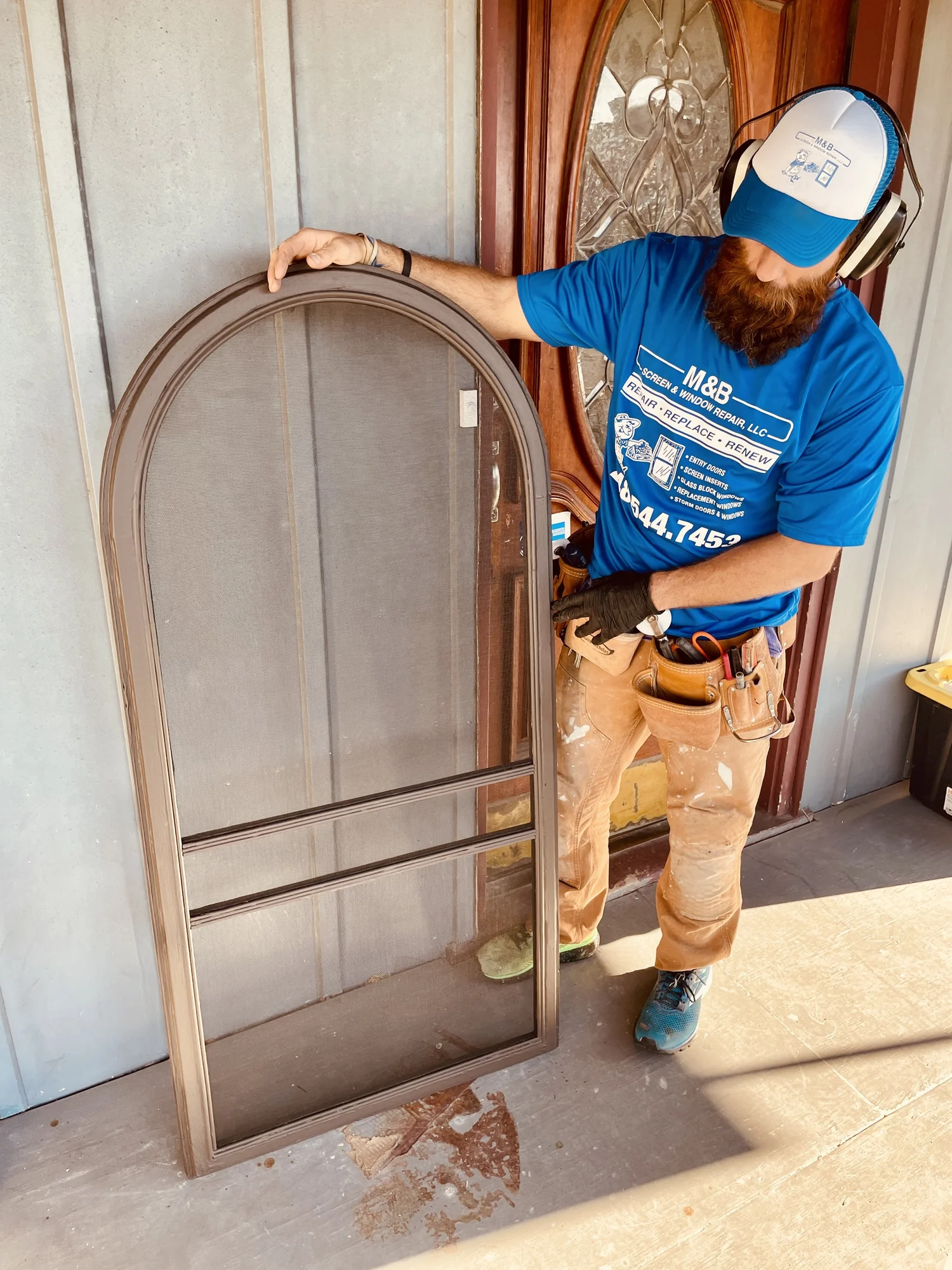 M&B technician holding a repaired screen door