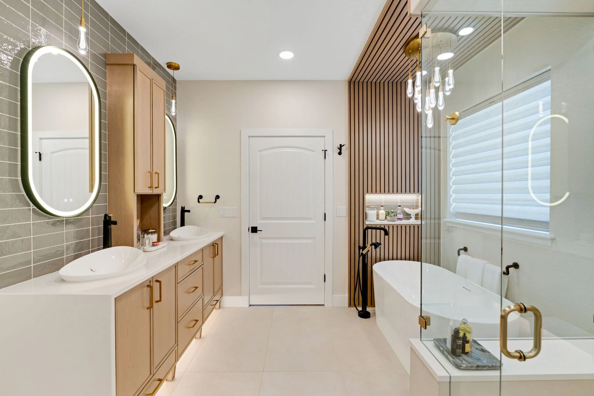 PRIMARY BATHROOM, SLATTED WALL, FREESTANDING BATHTUB, DECORATIVE LIGHT FIXTURESMAPLE CABINETS, DECORATIVE FIXTURES, TILE WAINSCOT, LIT MIRRORS