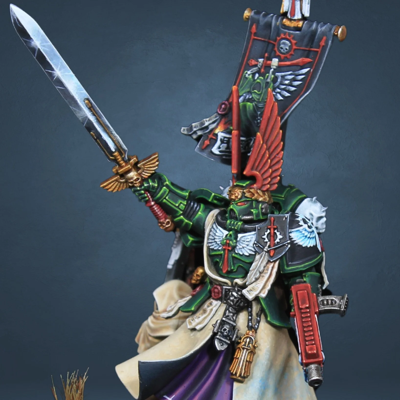 Miniature figure of a space marine in green armor with a sword and banner.