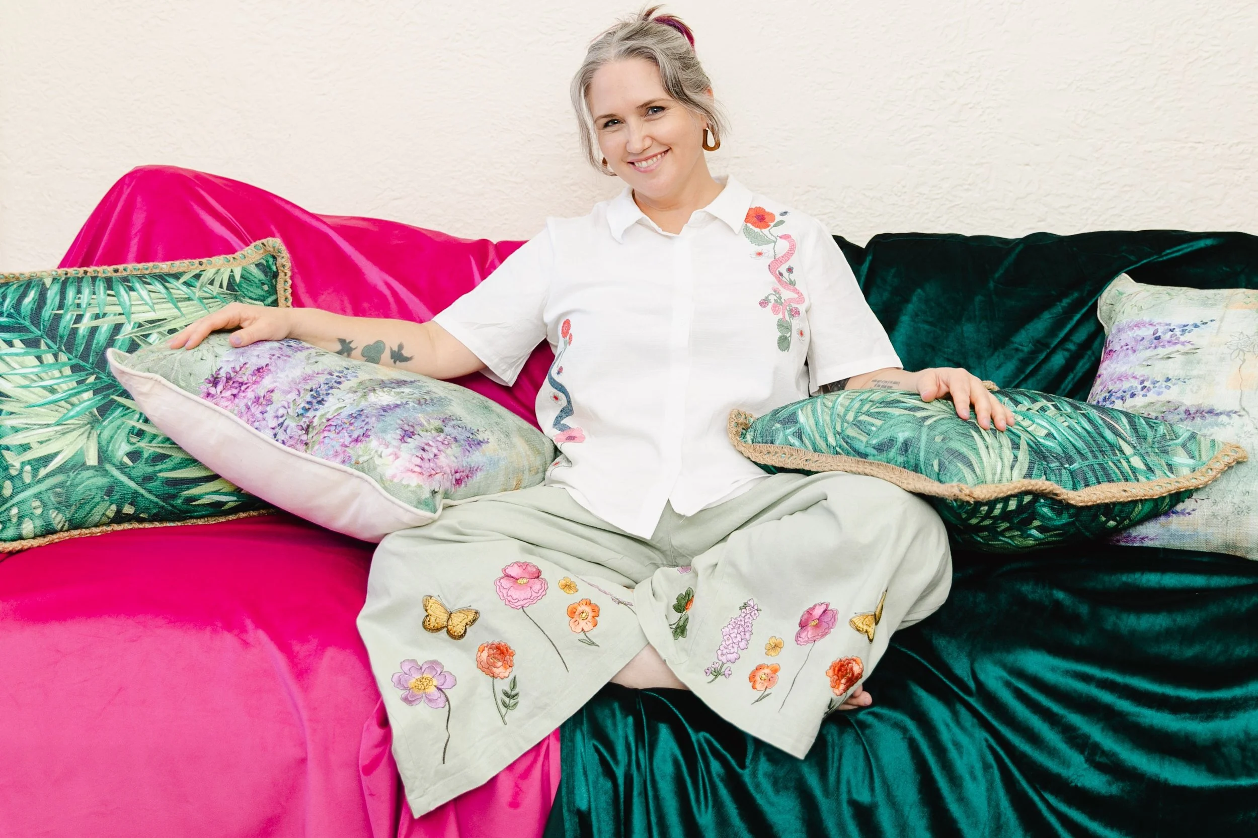 Person seated on a couch with colourful cushions, smiling and relaxed in a workshop-style setting.