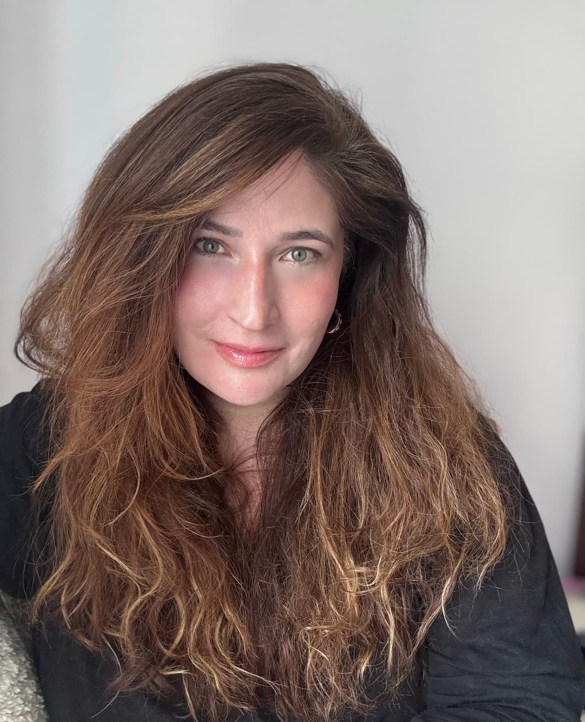 American therapist with long wavy brown hair, smiling warmly