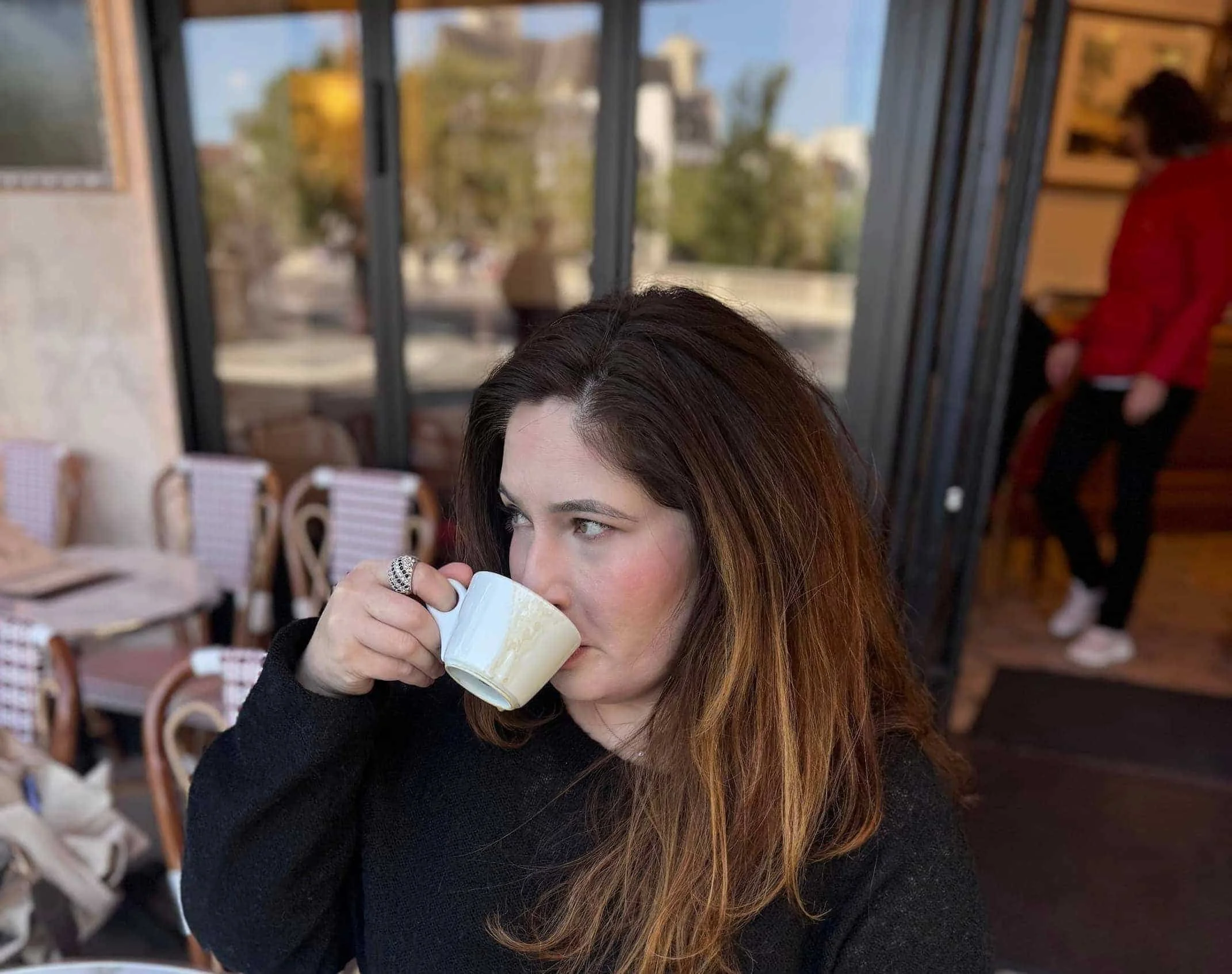 therapist with long brown hair drinking coffee at a cafe