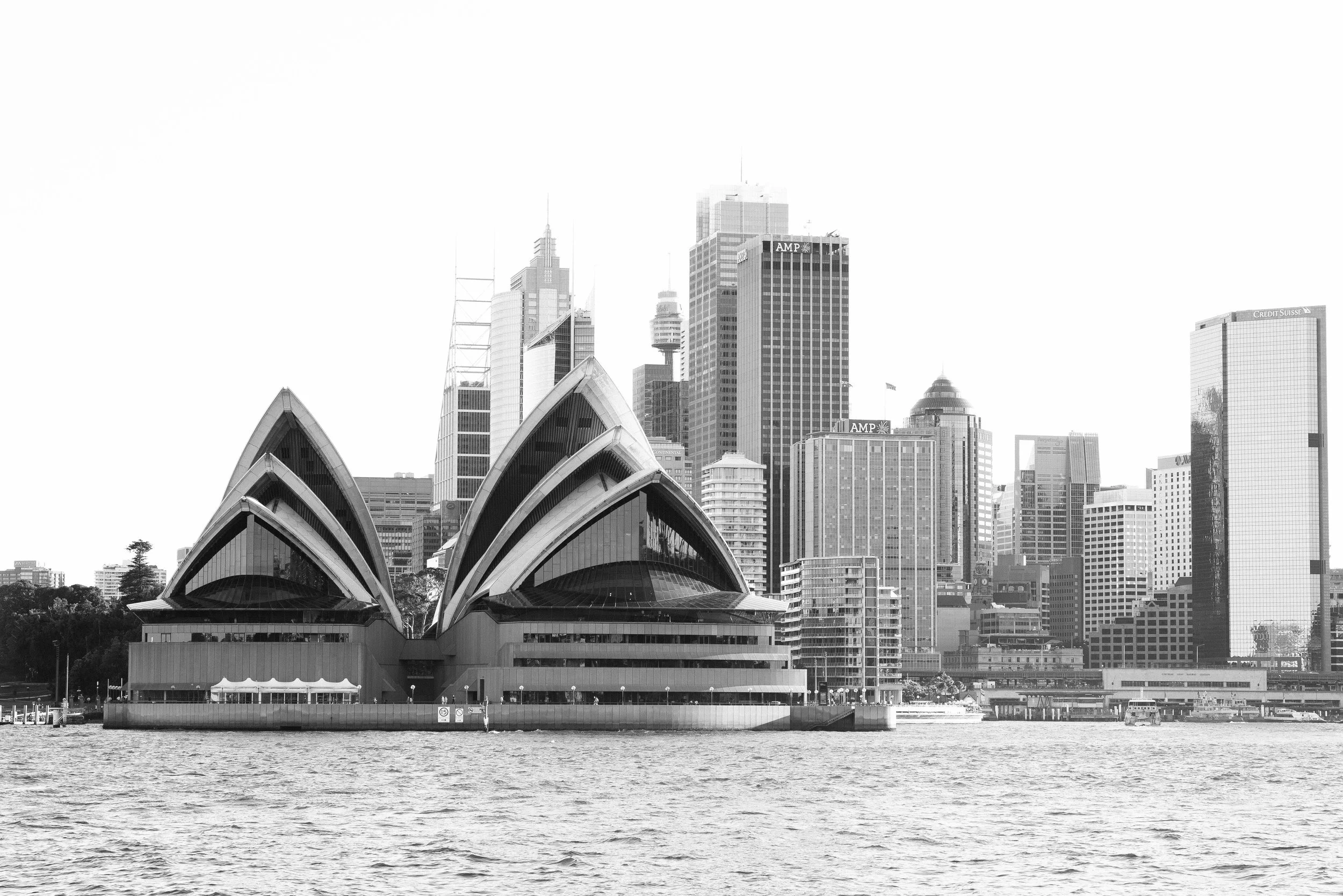 Black and white photo of the Sydney Opera House with a city skyline in the background.