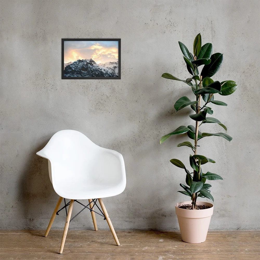 Schnee und Himmel im schwarzen Rahmen über einem weissen Stuhl neben einer Pflanze. Raumvisualisierung / Snow and sky, framed photograph shown in a room mockup.