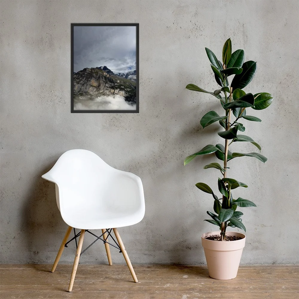 Wolkengrenze im schwarzen Rahmen mit Stuhl und Pflanze. Framed photograph with chair and plant; room mockup.
