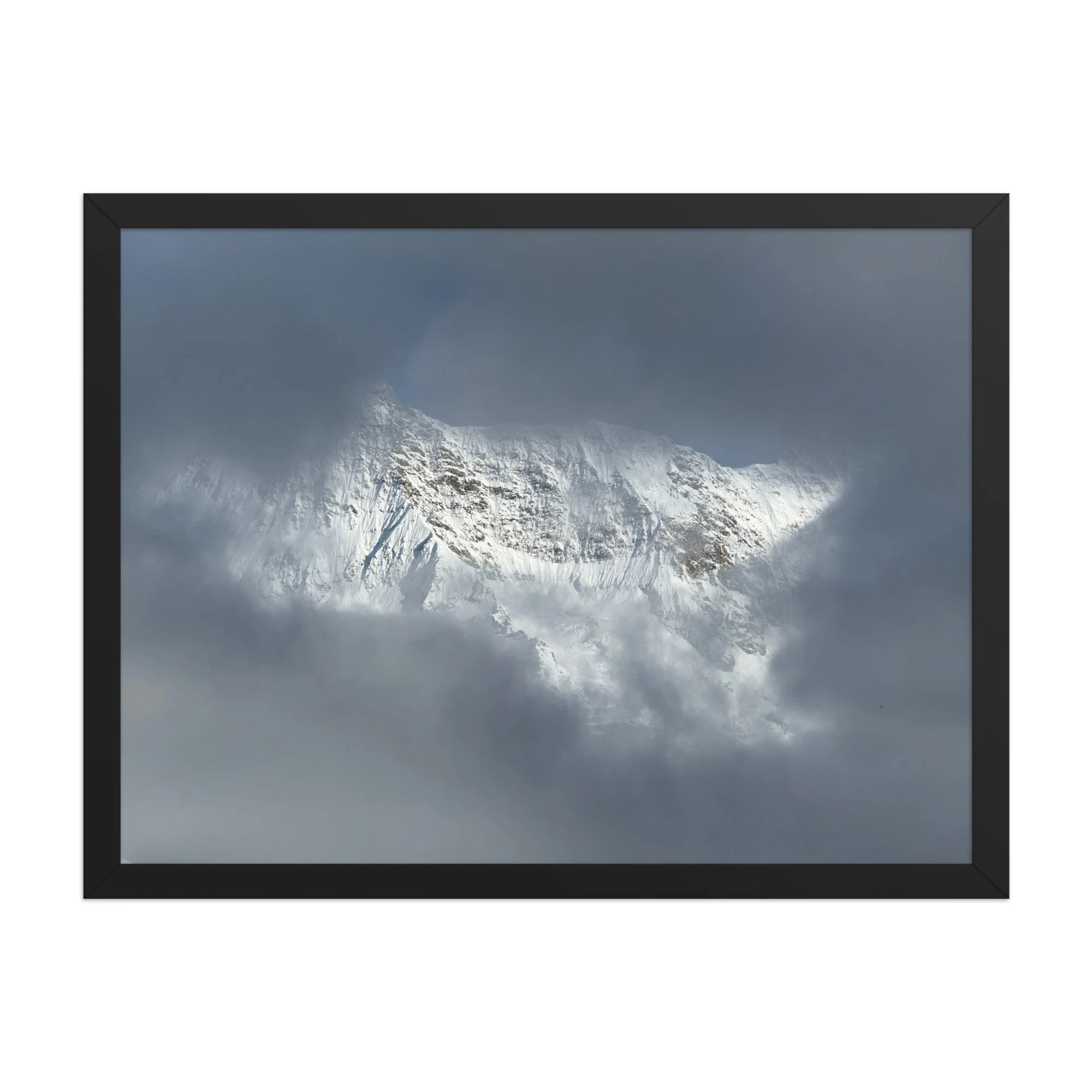 Licht auf verschneitem Fels zwischen dunklen Wolken, schwarzer Rahmen. Sunlit snowy rock through clouds, black frame.