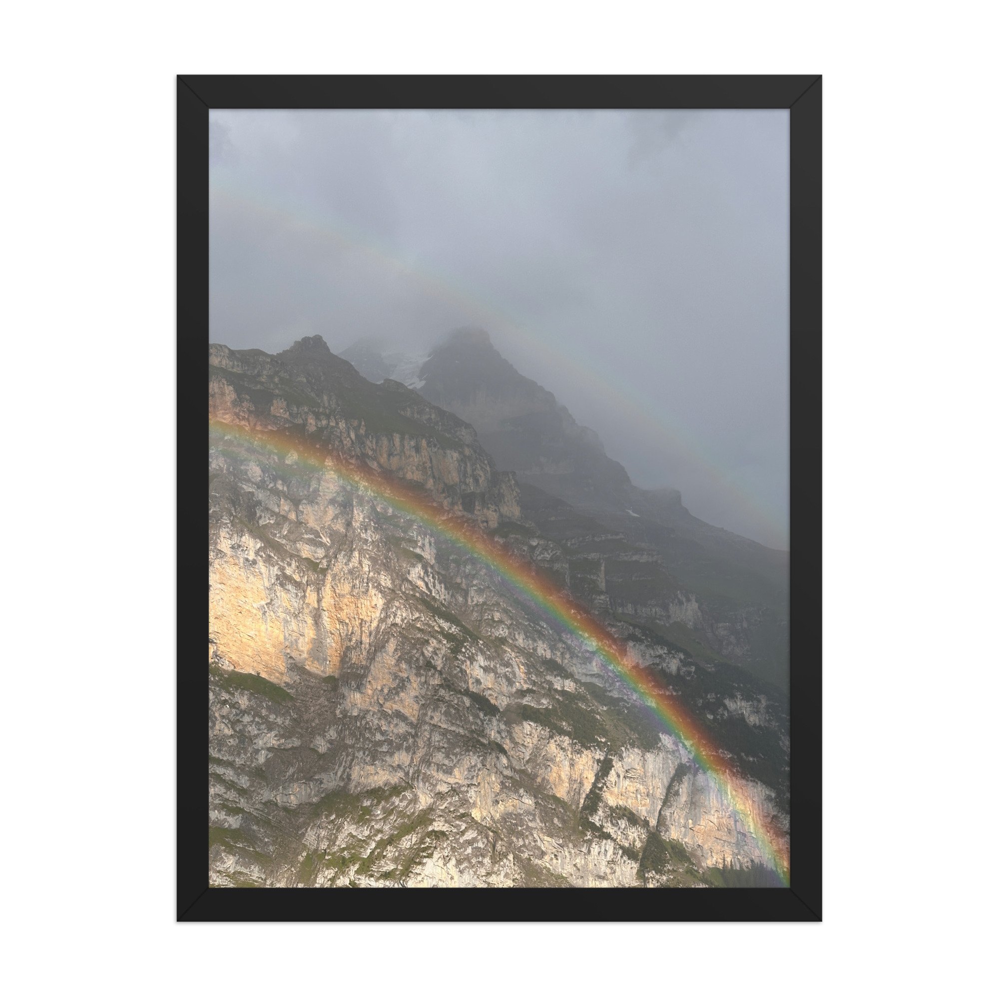 Regenbogen vor heller Felswand, schwarzer Rahmen. Rainbow across a rock face, black frame.