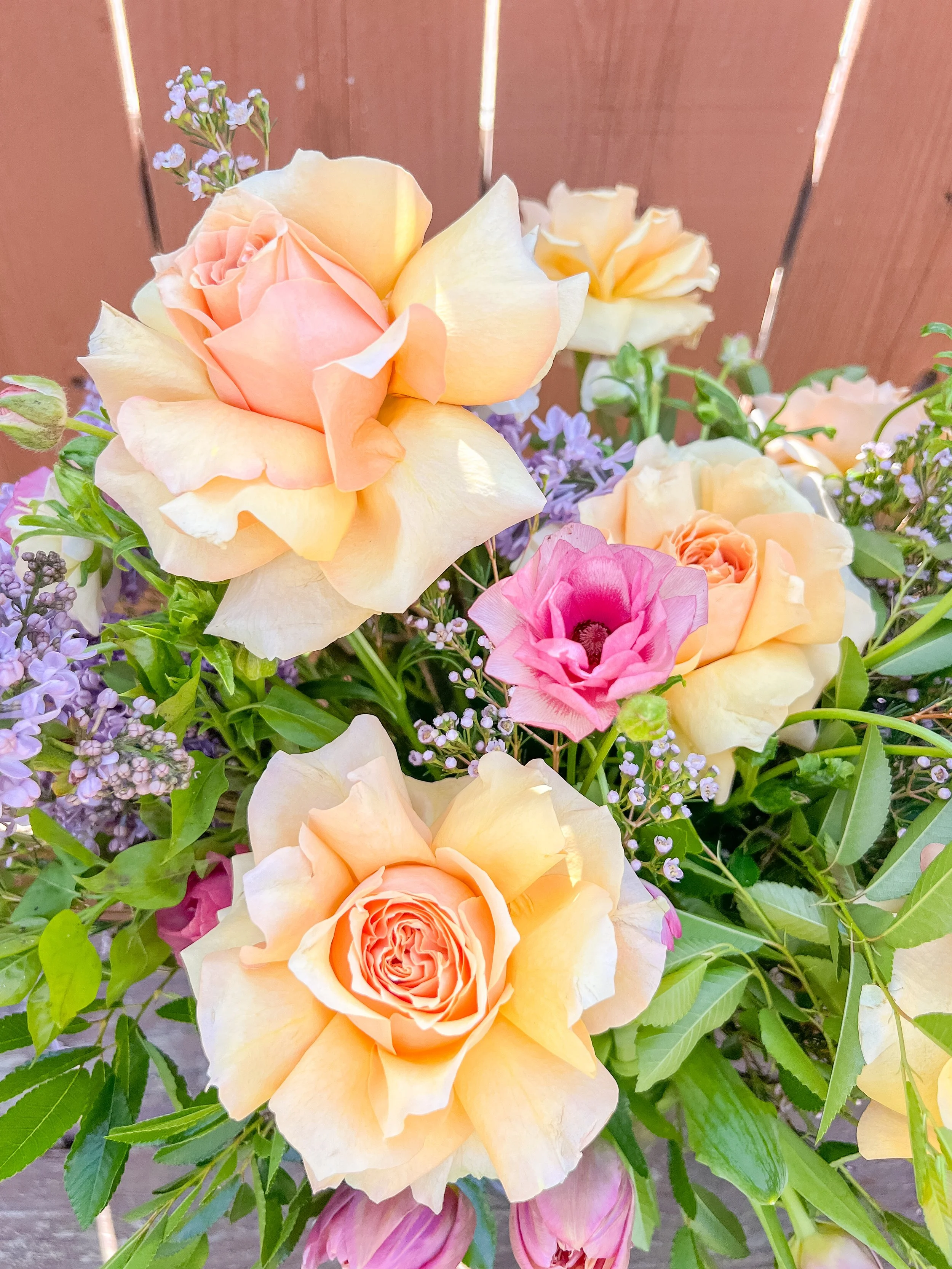 Colorful bouquet of roses and other flowers with a wooden background.