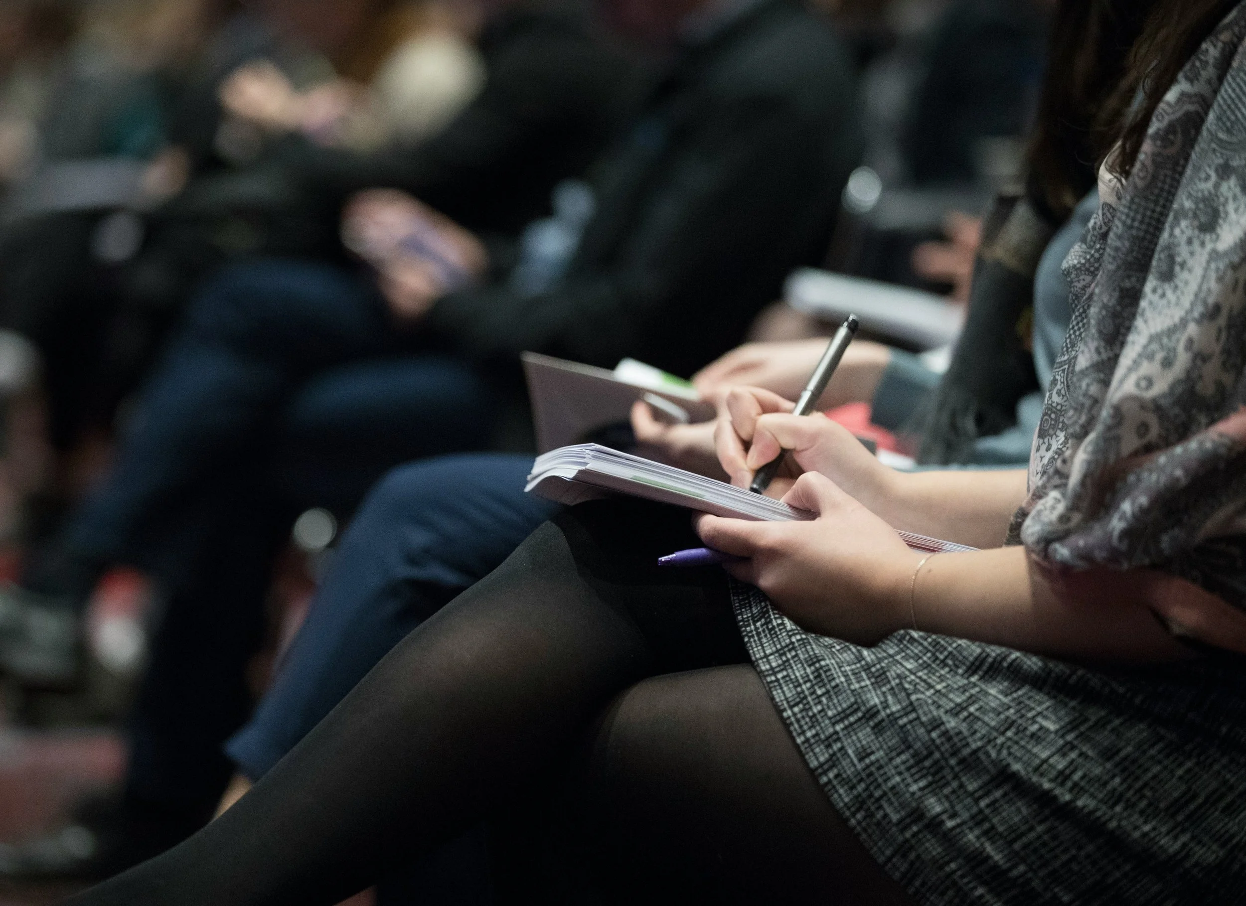 Participant·e prenant des notes lors d’une conférence animée par les Médianes.