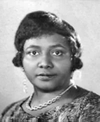 Portrait noir et blanc d'une femme afro-américaine portant un collier, avec des cheveux courts et une expression neutre.