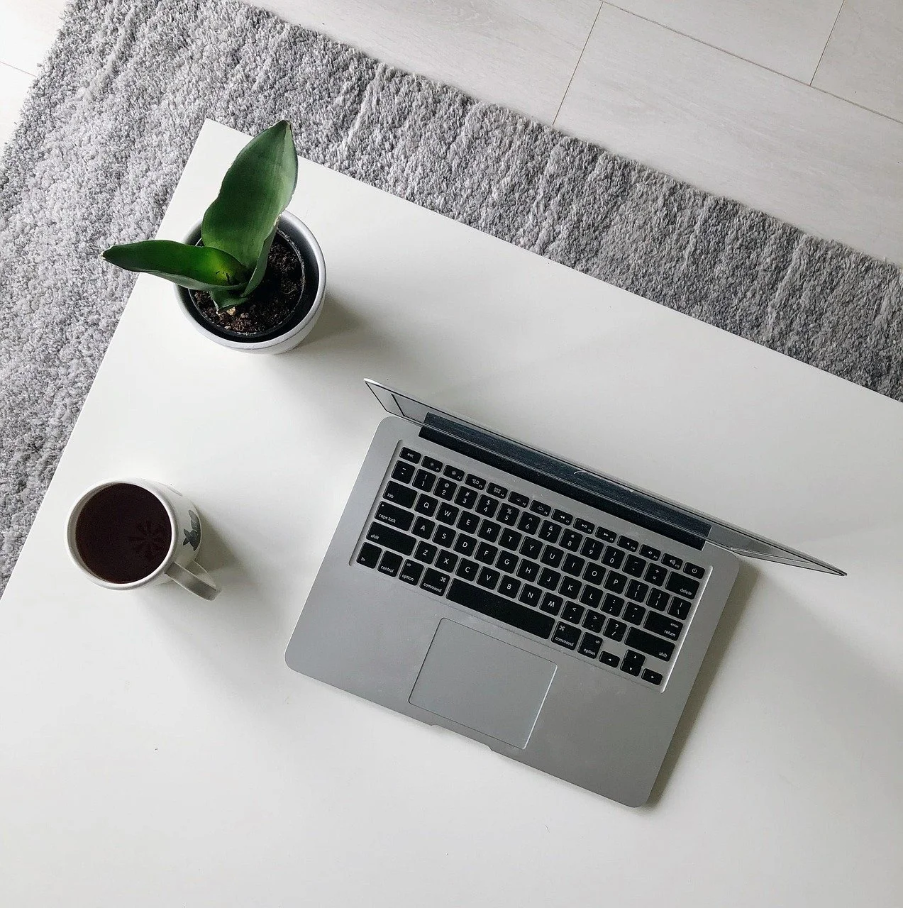 computer met koffie en plant op tafel
