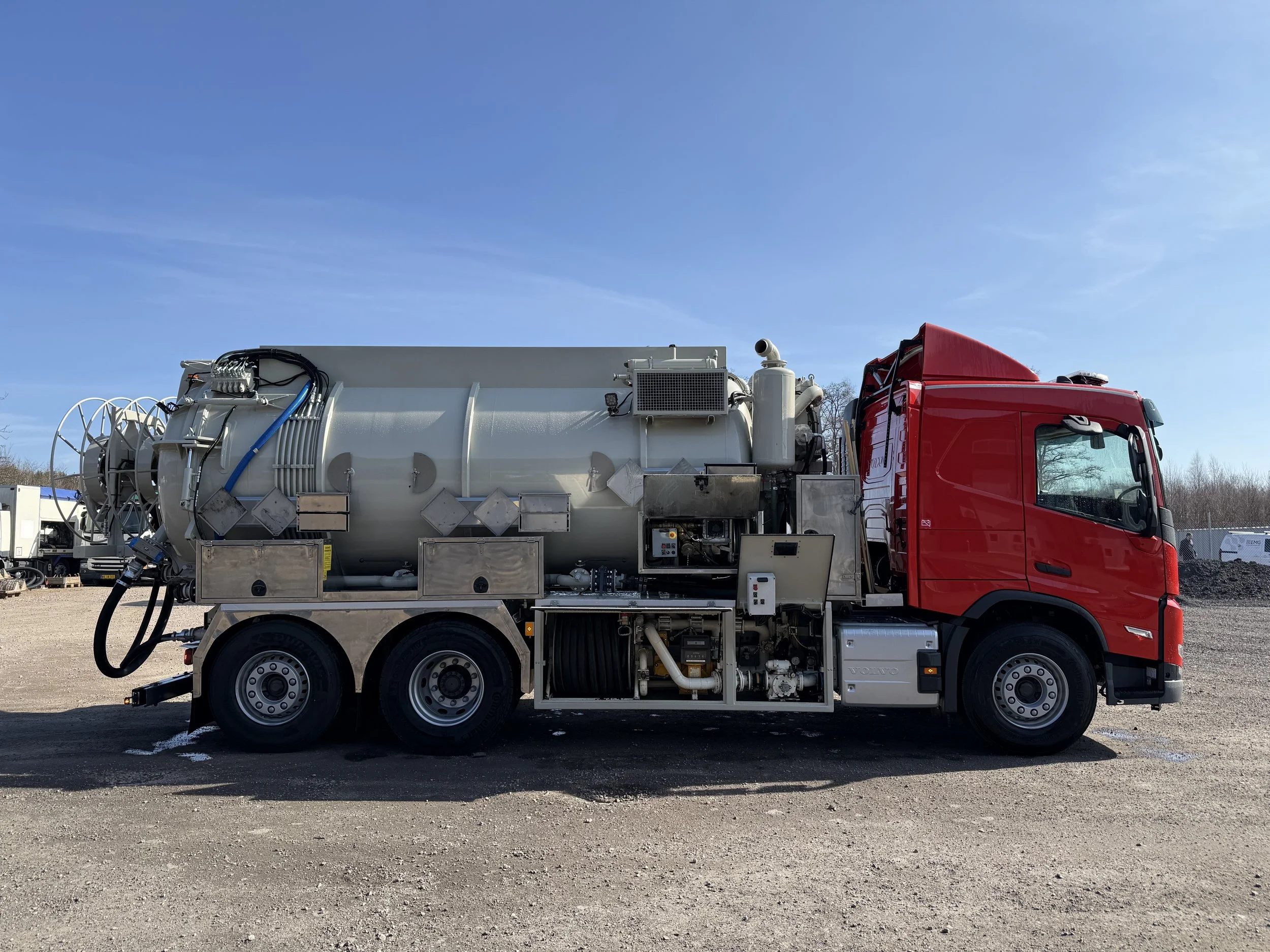 Slamsug med vakuumtank, sida, under klarblå himmel.