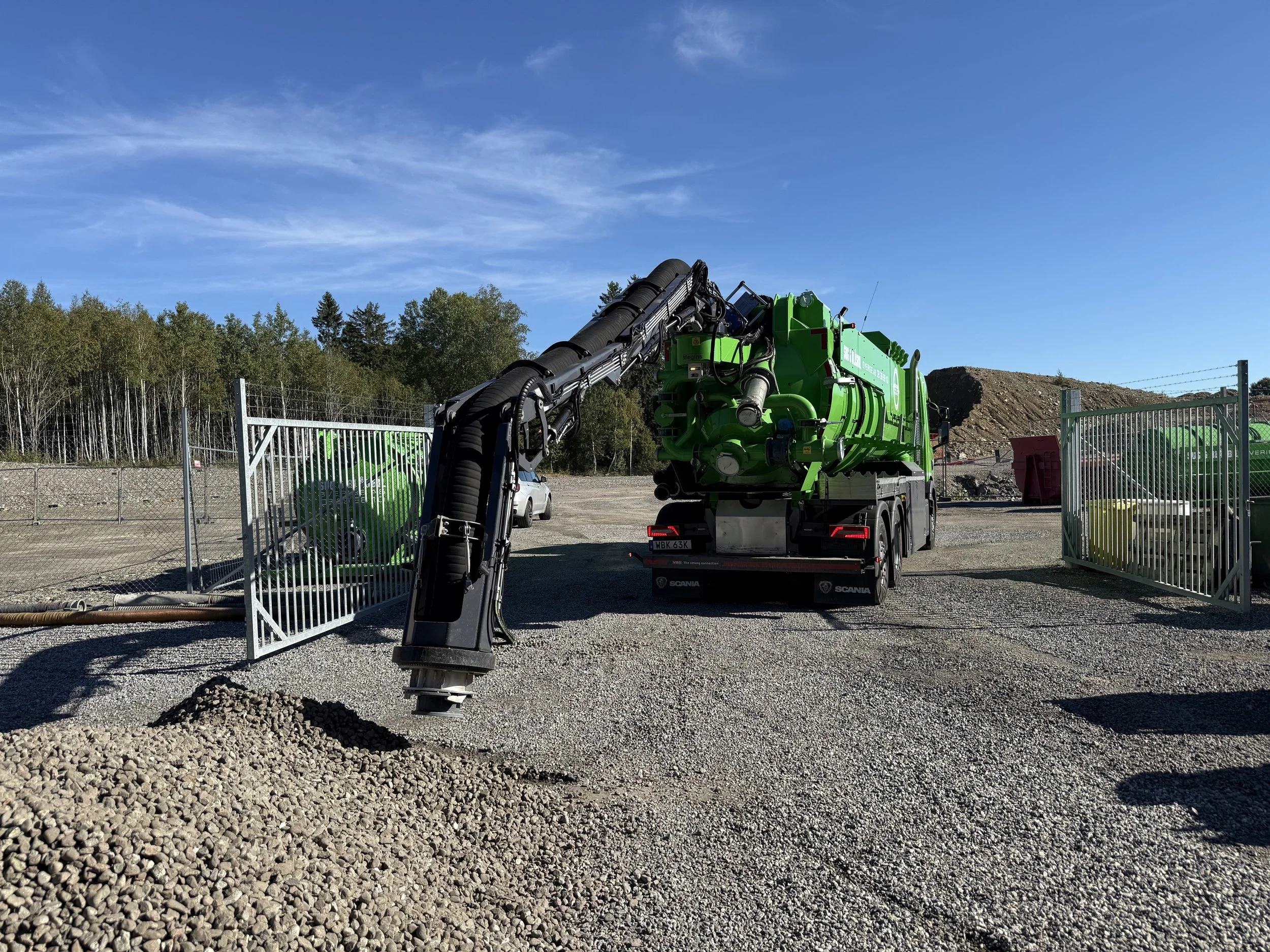 En grön vakuumlastare från Megins med flexibel arm på bakluckan.