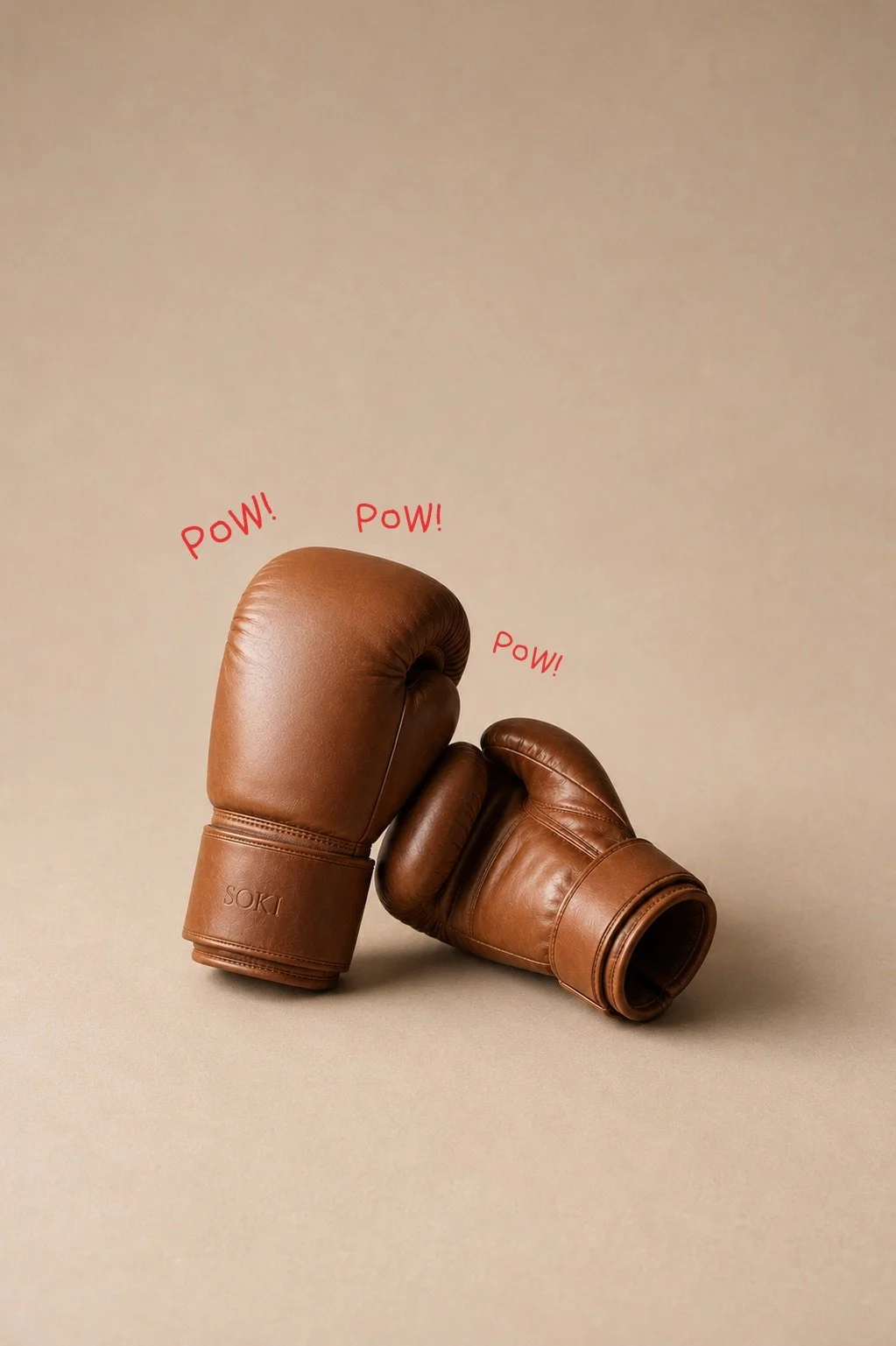 A pair of brown boxing gloves with the word "SOKI" on the wrist strap, positioned as if in a fight, with three red "POW!" sound effects around them.