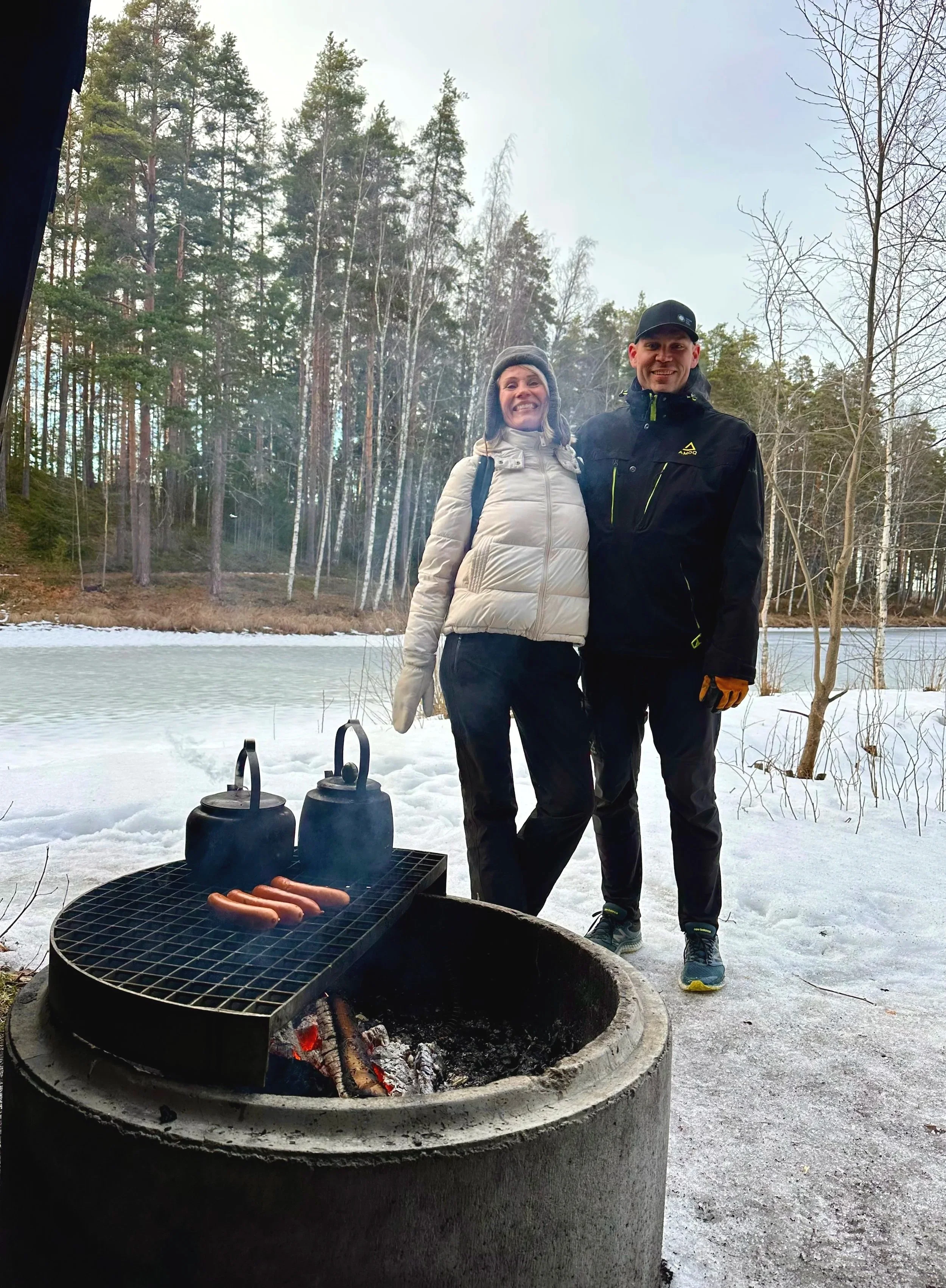 Mirka Kristiina Bruun and Teemu Virtanen by an open fire during a Sisu leadership experience in the Finnish forest, reflecting and connecting in nature
