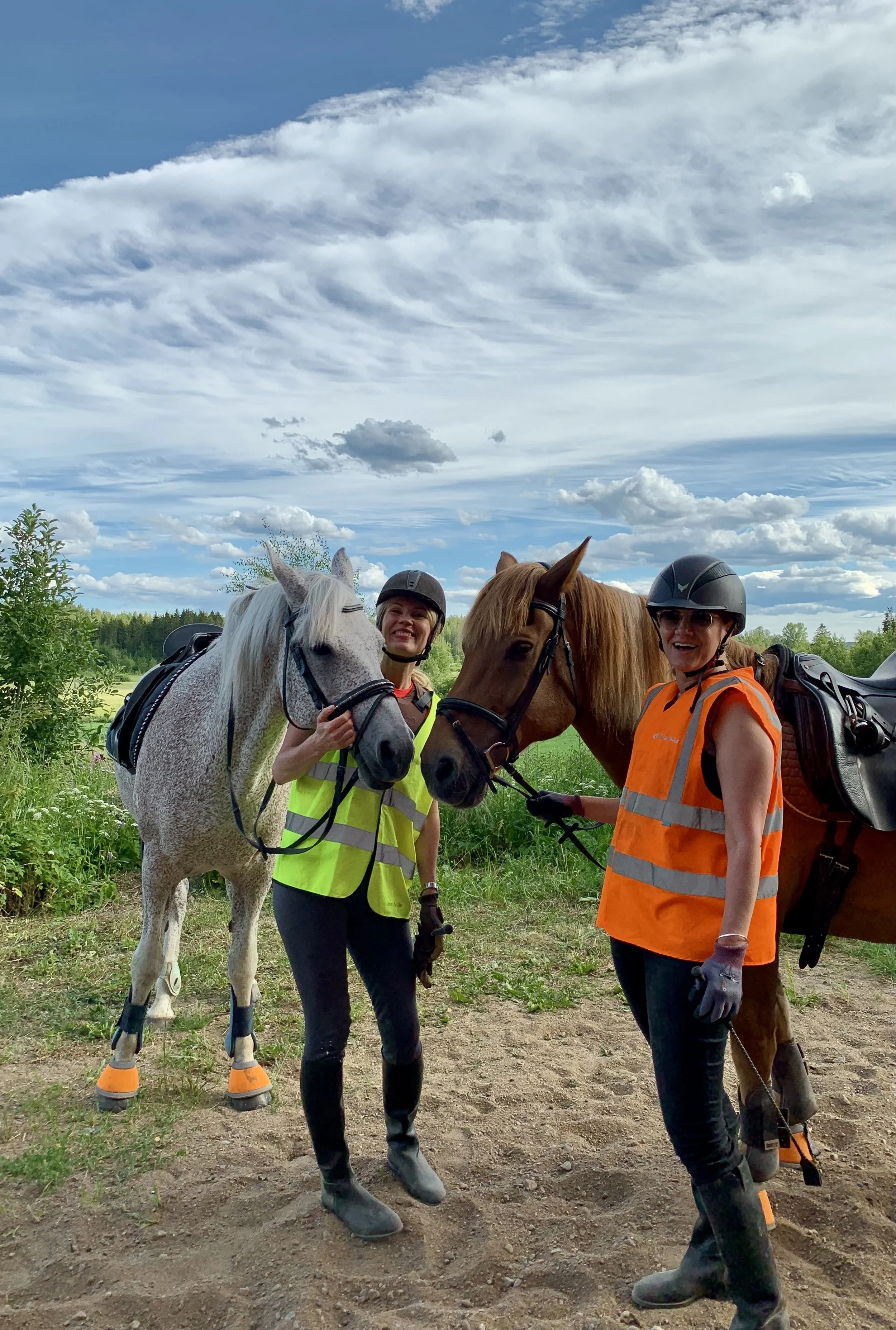 Two riders connecting with their horses in the quiet Finnish countryside during a Lake Saimaa horse retreat.