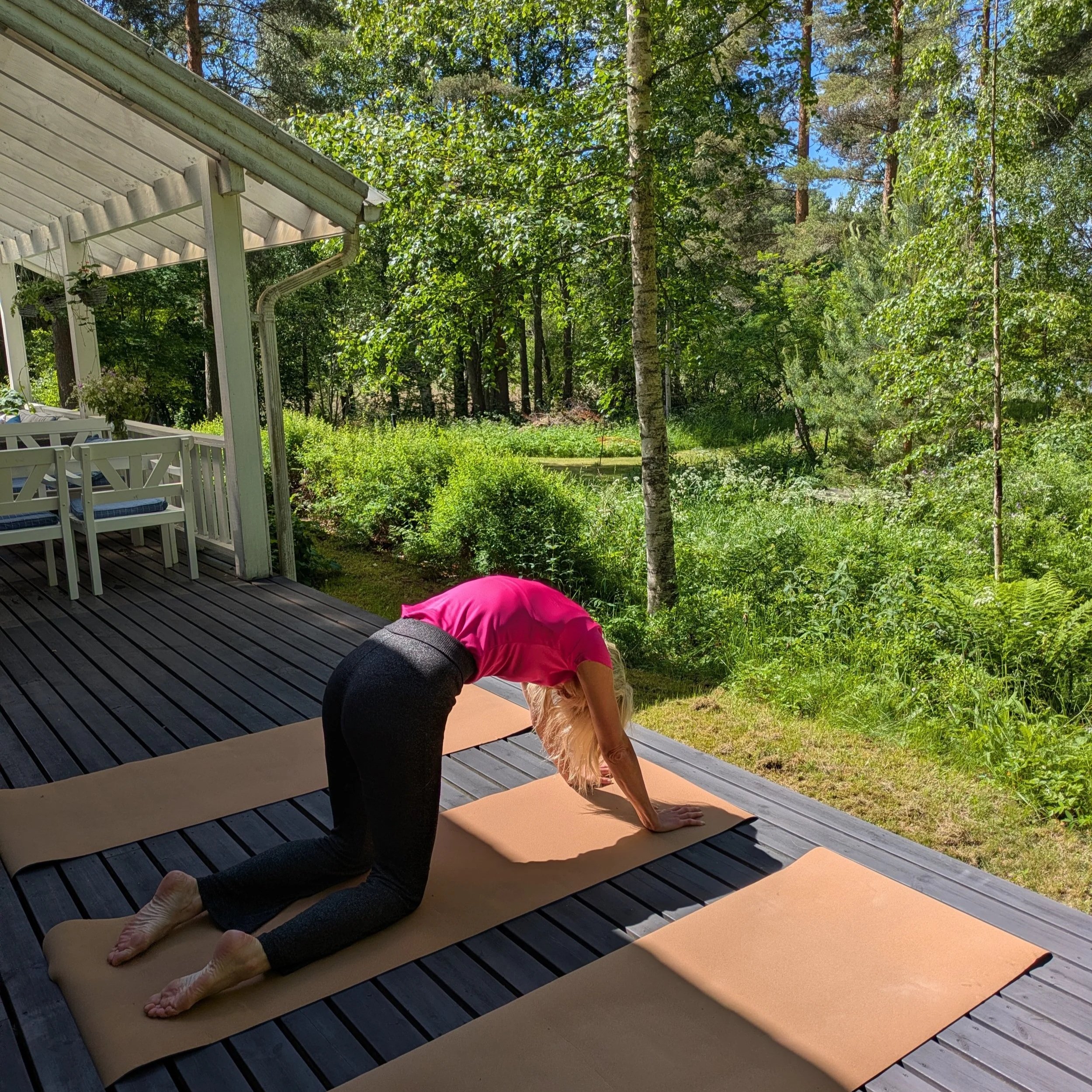 A guest practices Pilates on a cork yoga mat on the terrace at Blueberry Villa, surrounded by forest and the peaceful sounds of nature. The tranquil setting in the Finnish Lakeland offers a quiet space to move mindfully, breathe deeply, and reconnect
