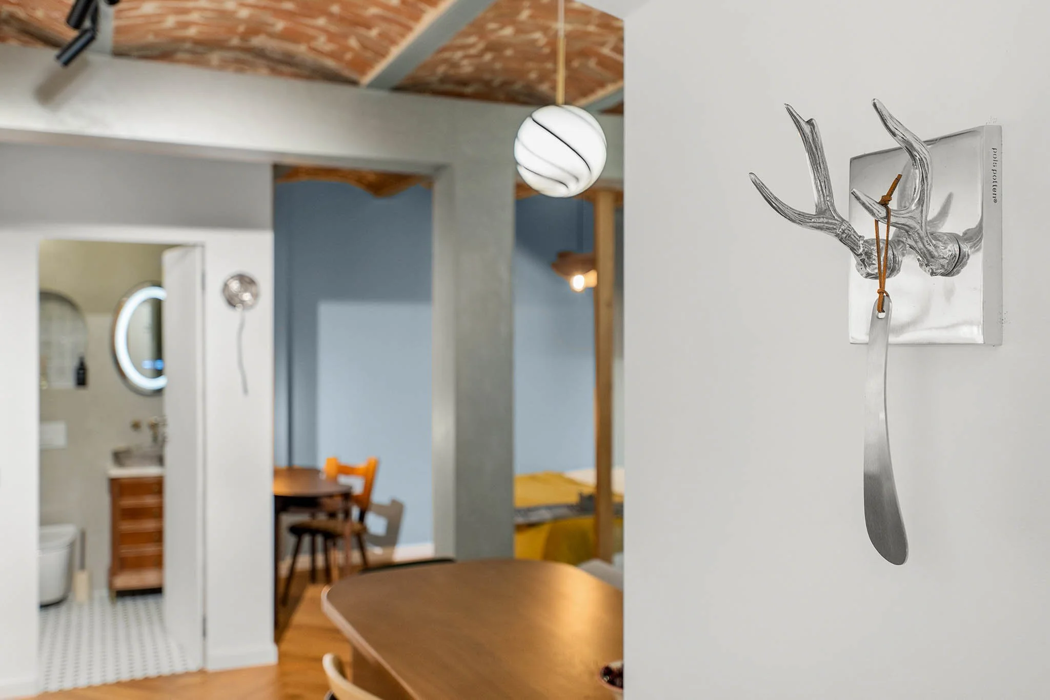Decorative wall art of a metallic deer antlers with a hanging leather strap in a cozy modern living space.