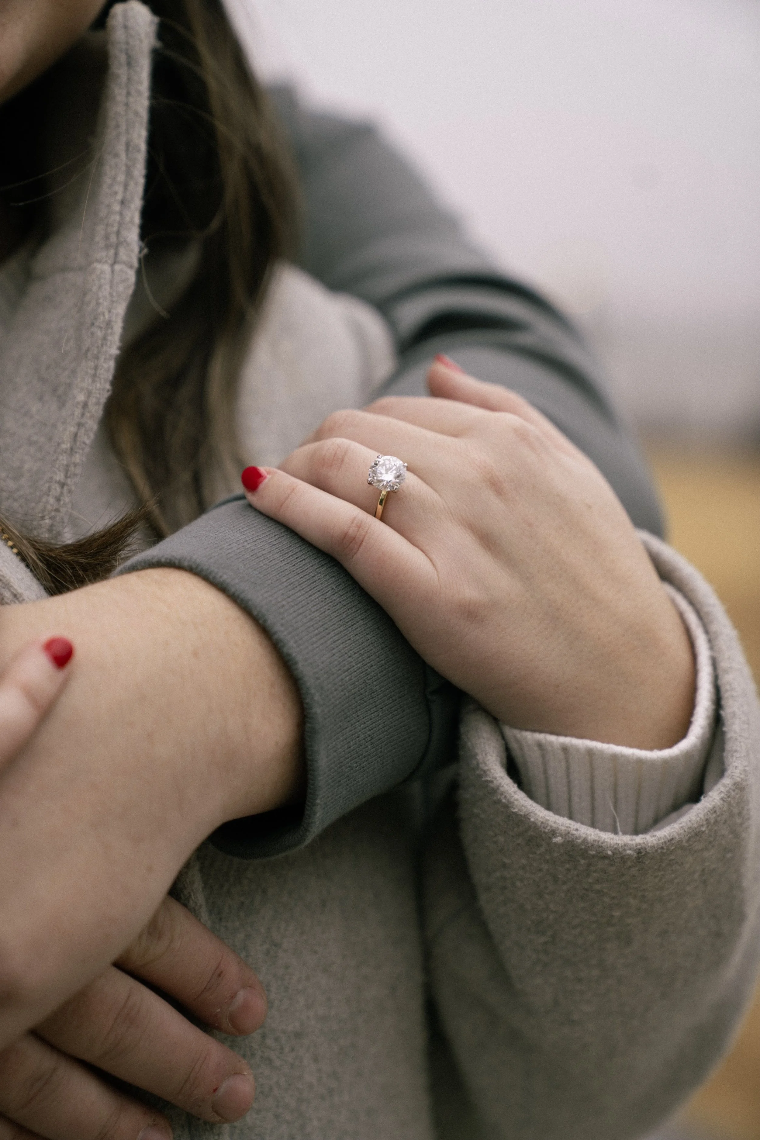 A close-up of a woman showing a large engagement ring on her left hand, resting on another person's arm. Engagement photography Atlanta, Decatur, Georgia,