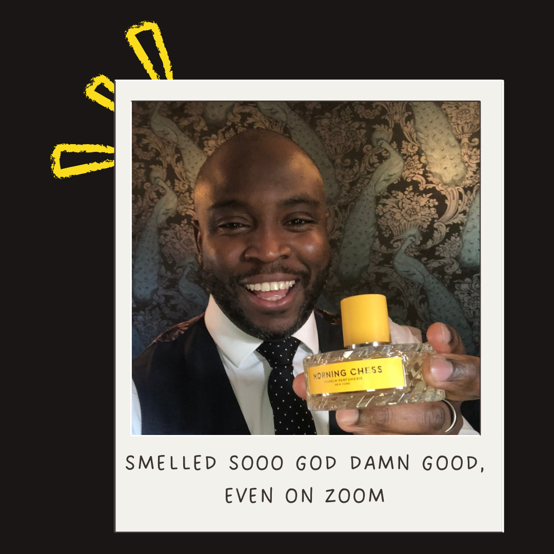 A man in a suit holding a bottle of perfume labeled 'Morning Chess' with a happy expression, against a patterned background with yellow doodles.