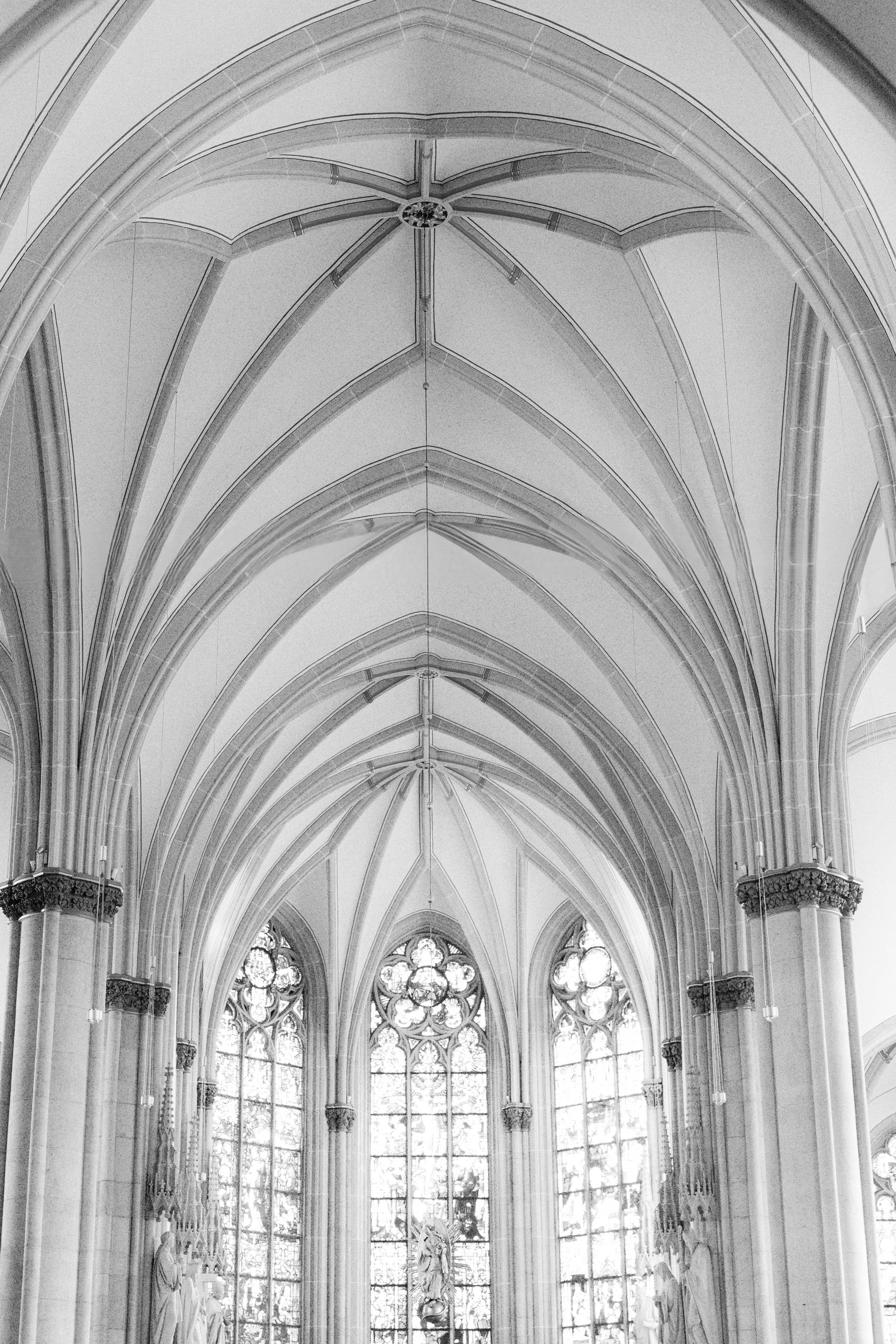 Innenaufnahme einer gotischen Kathedrale mit hohen Spitzbögen, großen bunten Fenster und Skulpturen