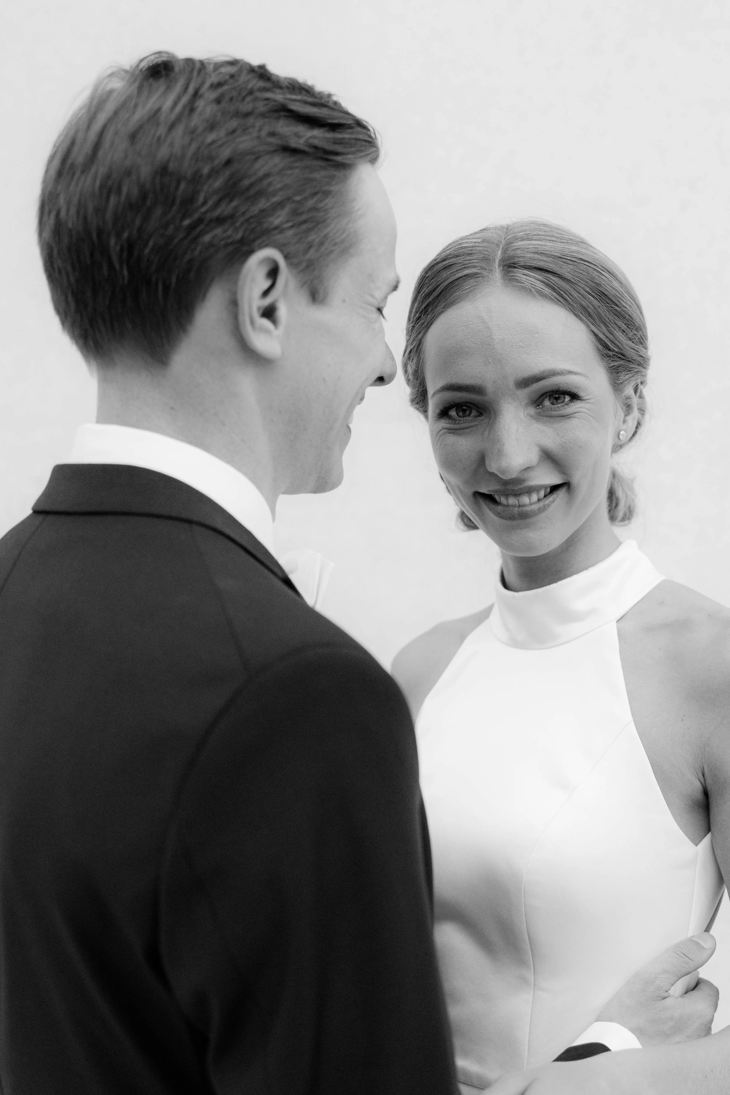 Ein Mann und eine Frau bei einer Hochzeit, die sich anblicken, die Frau lächelt.