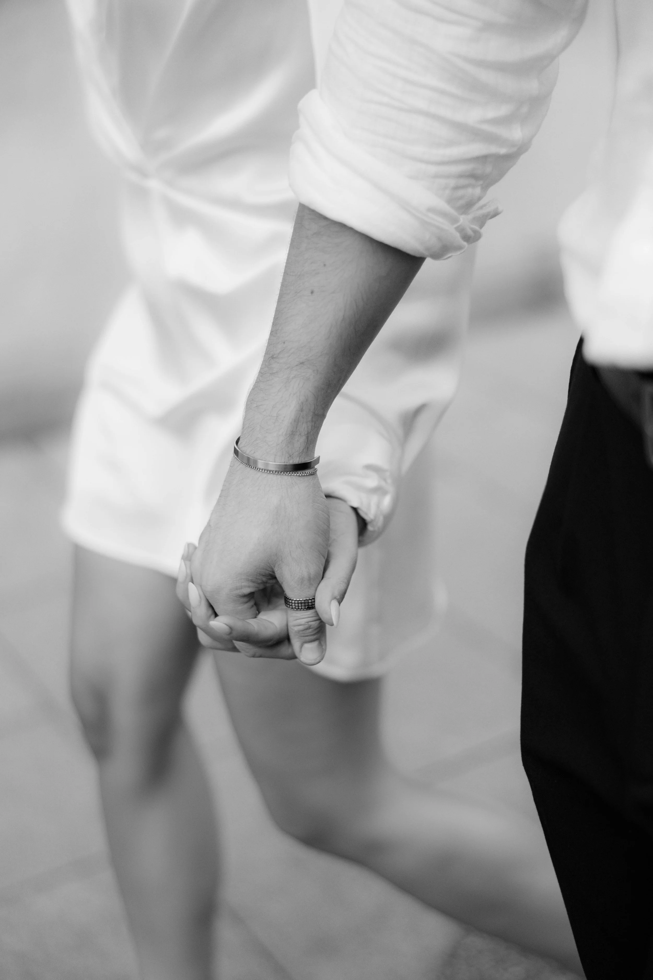 Nahaufnahme von einem Paar, das sich an den Händen hält, vermutlich bei einem Tanz, in Schwarz-Weiß-Fotografie.