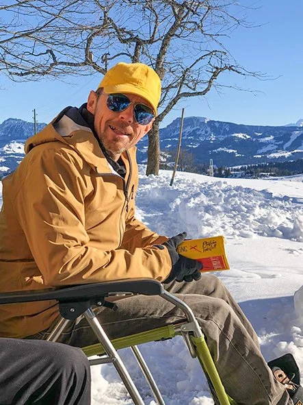 Adrian Knaup liest im Schnee bei schönem Wetter.