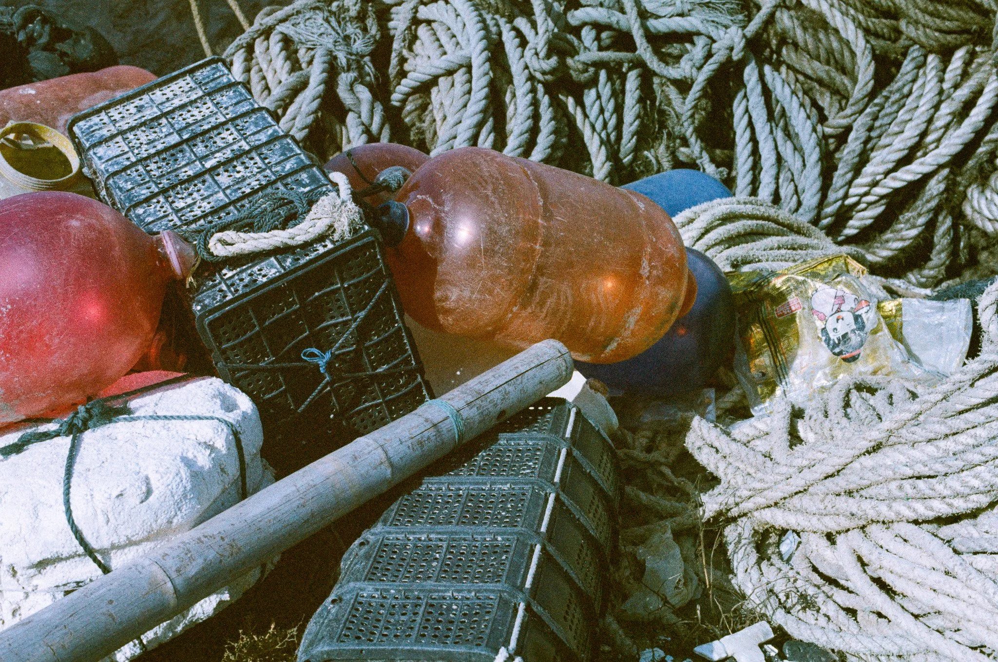 Litter and debris, including plastic bottles, ropes, and a pipe, entangled among rocks and coils of rope.