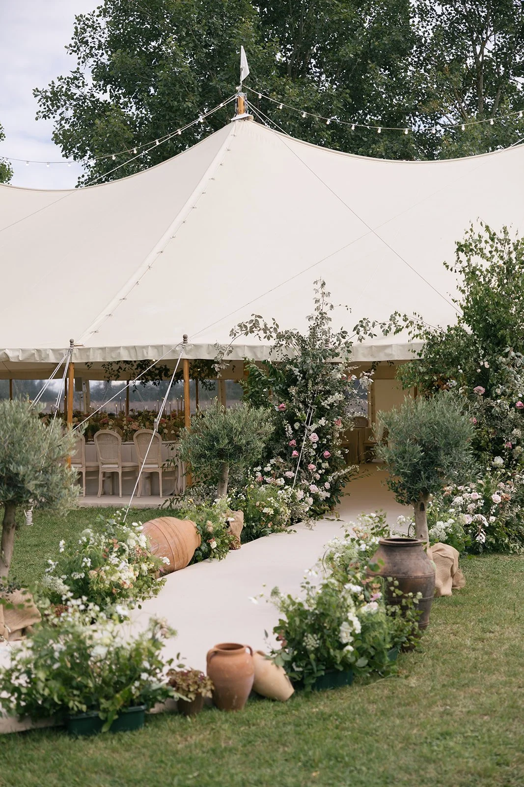 sail-and-peg-luxury-sailcloth-marquee-bespoke-curved-walkway-entrance-garden-entrance-olive-trees-urns-floral.jpg