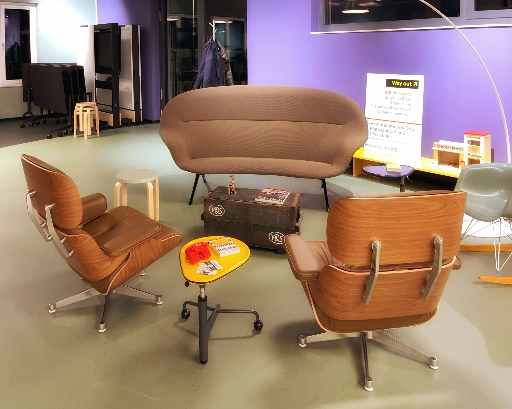 Ein Loungebereich mit gemütlichen Sesseln, einem kleinen Tisch mit Spielzeug und Zeitschriften, einem größeren Mitteltisch und einem Fernseher an der Wand.