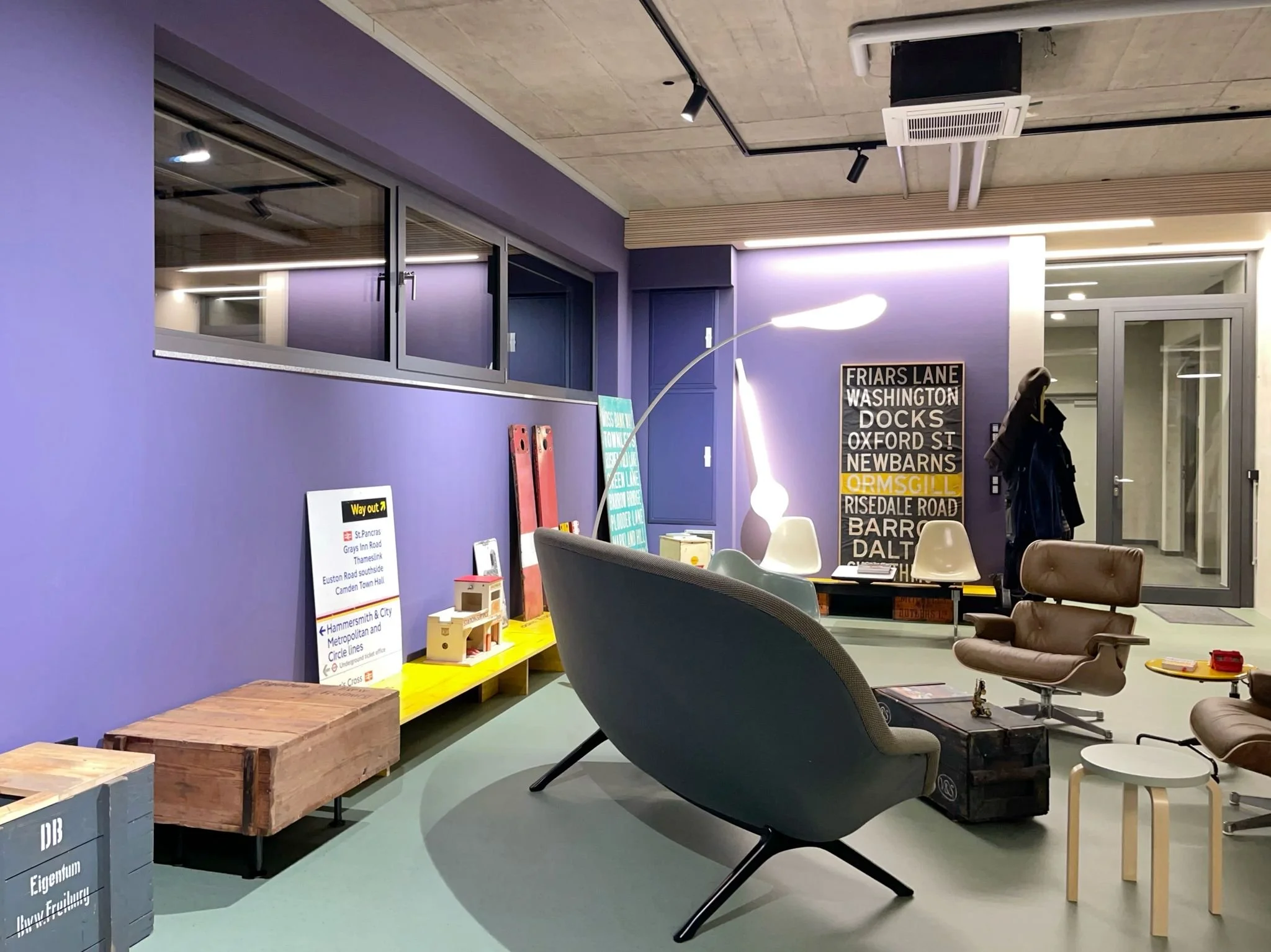 Moderner Veranstaltungsraum mit bunten Wänden, Sofas, Stühlen, Beleuchtung, Dekoration und Informationsschilder