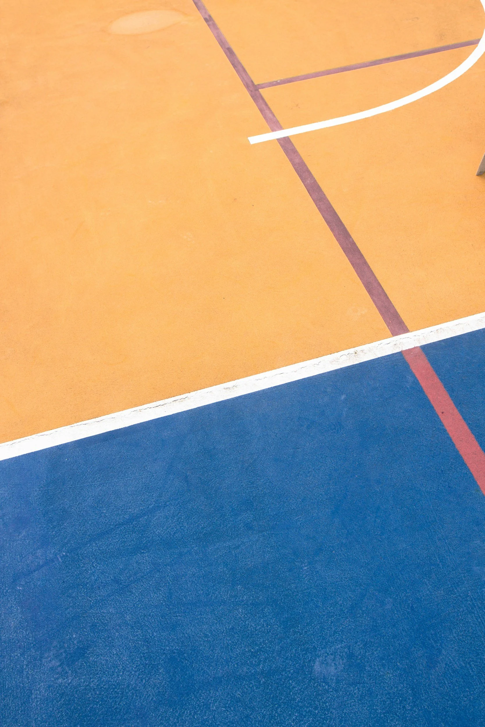 Close-up of a court with orange and blue sections, white boundary lines, and purple and red markings.