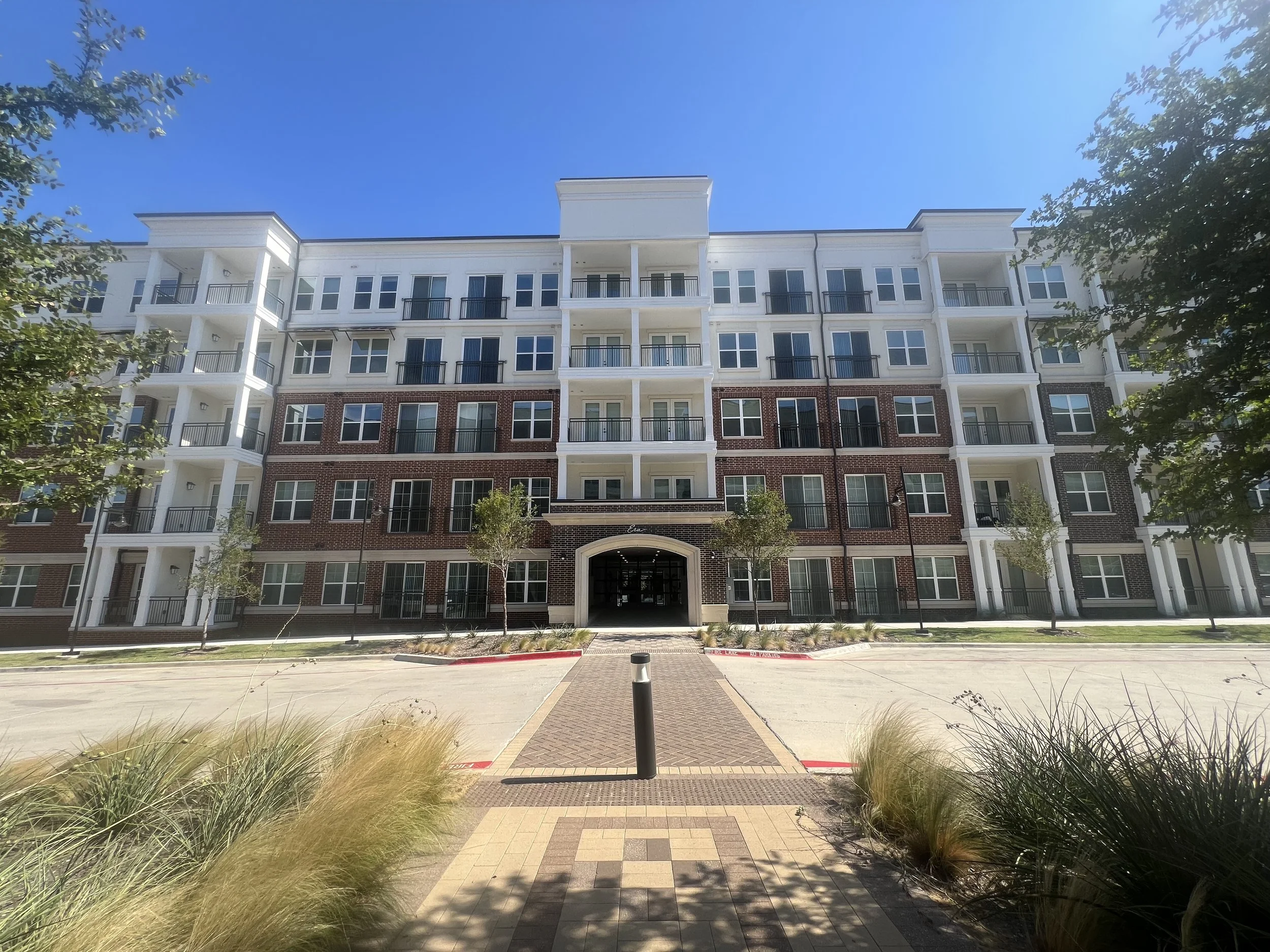 4,400 cubes of dry tamp cast stone form the banding, columns, and cornice courses at ERA Denton. A 2026 Cast Stone Excellence Awards entry.