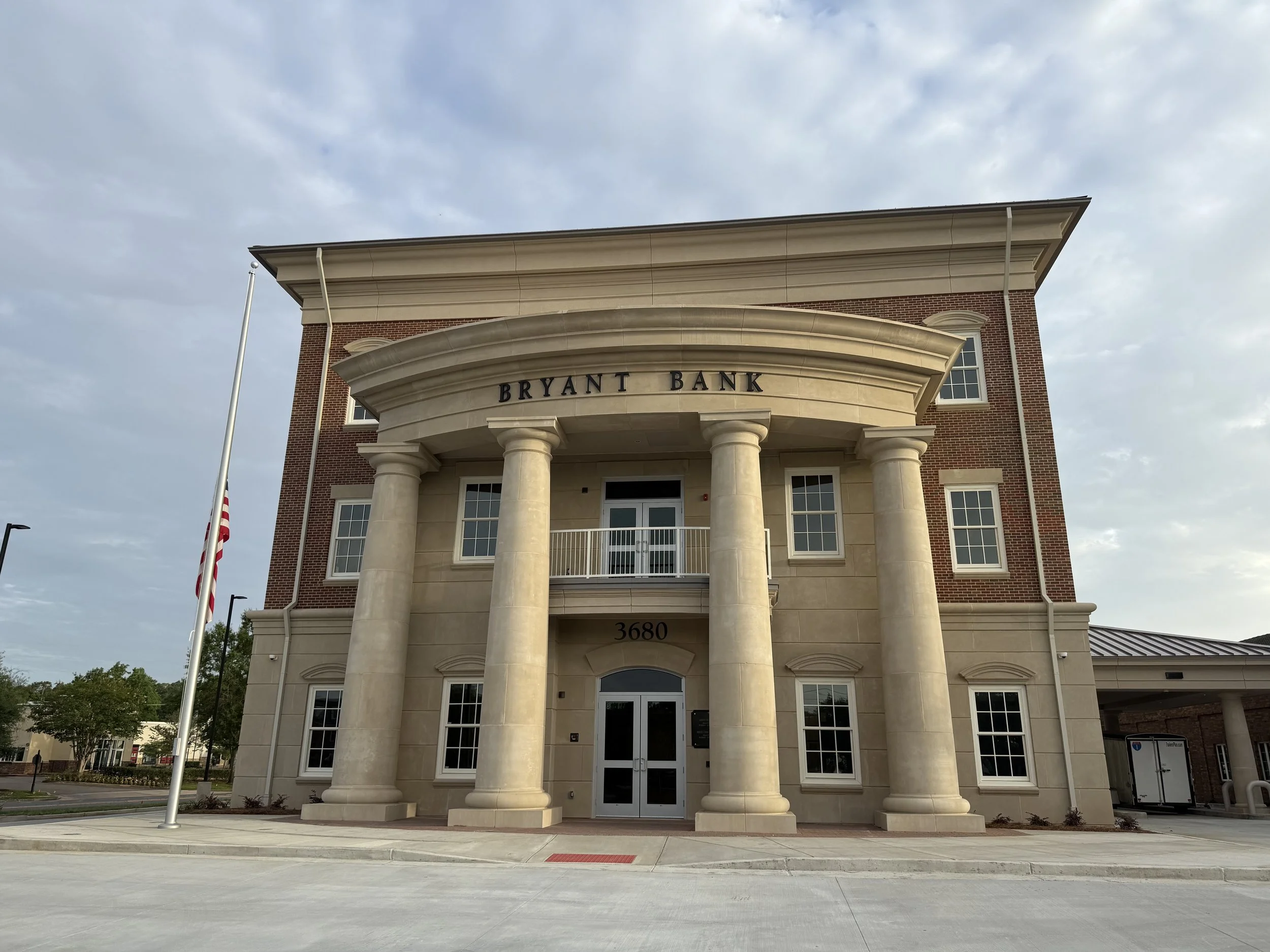 Cast stone columns, headers, cornice, and veneer panels give Bryant Bank its sense of permanence. A 2026 Cast Stone Excellence Awards entry.