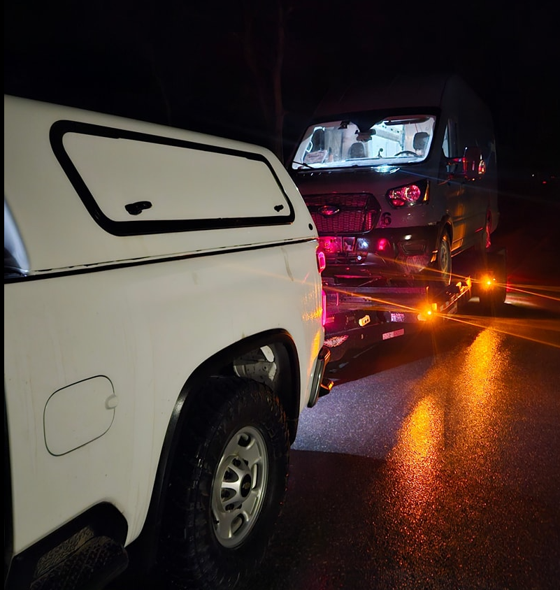 Pickup truck towing a van on a trailer at night