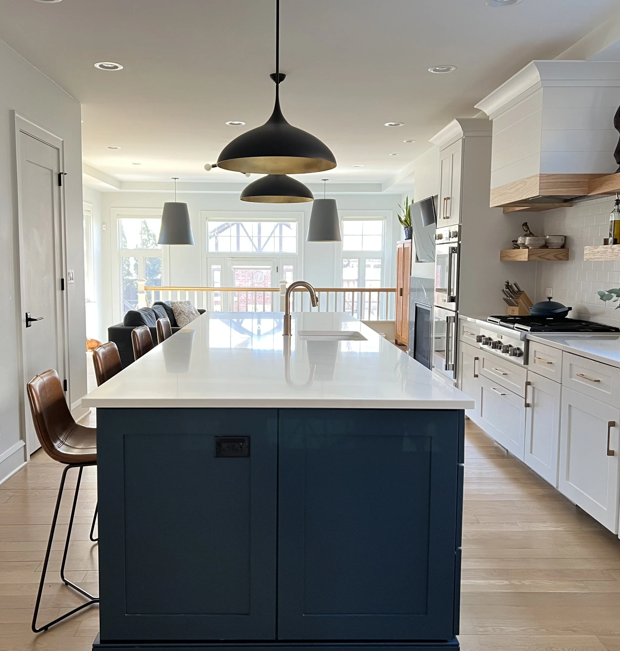 Modern kitchen with an island, pendant lights, bar stools, white cabinets, and stainless steel appliances.