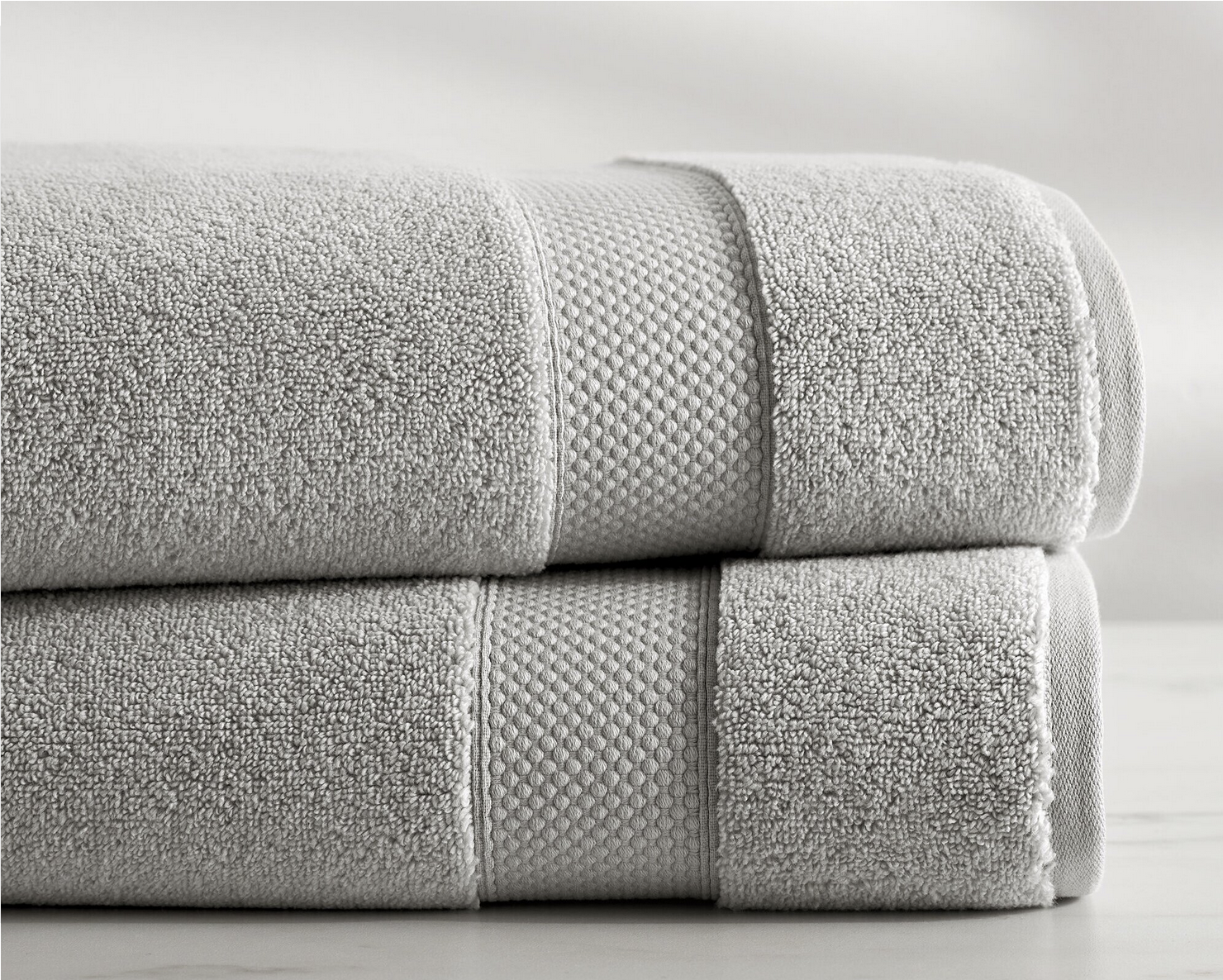 Two neatly folded beige towels with textured surfaces on a light surface