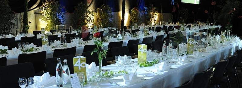 Festlich gedeckter Tisch bei einer Veranstaltung mit Blumen, Kerzen und dezenten Dekorationen.