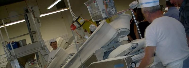 Menschen in einer Fleischerei, die Fleisch schneiden und verarbeiten.