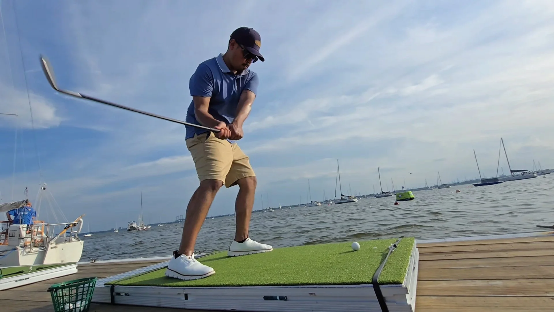 Boats docked at a marina during sunset with a calm water surface and hills in the background.