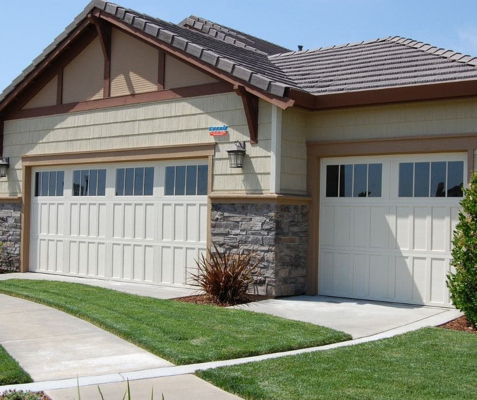 Front view of a suburban house with two-car garage, stone and wood facade, and a neatly maintained lawn.
