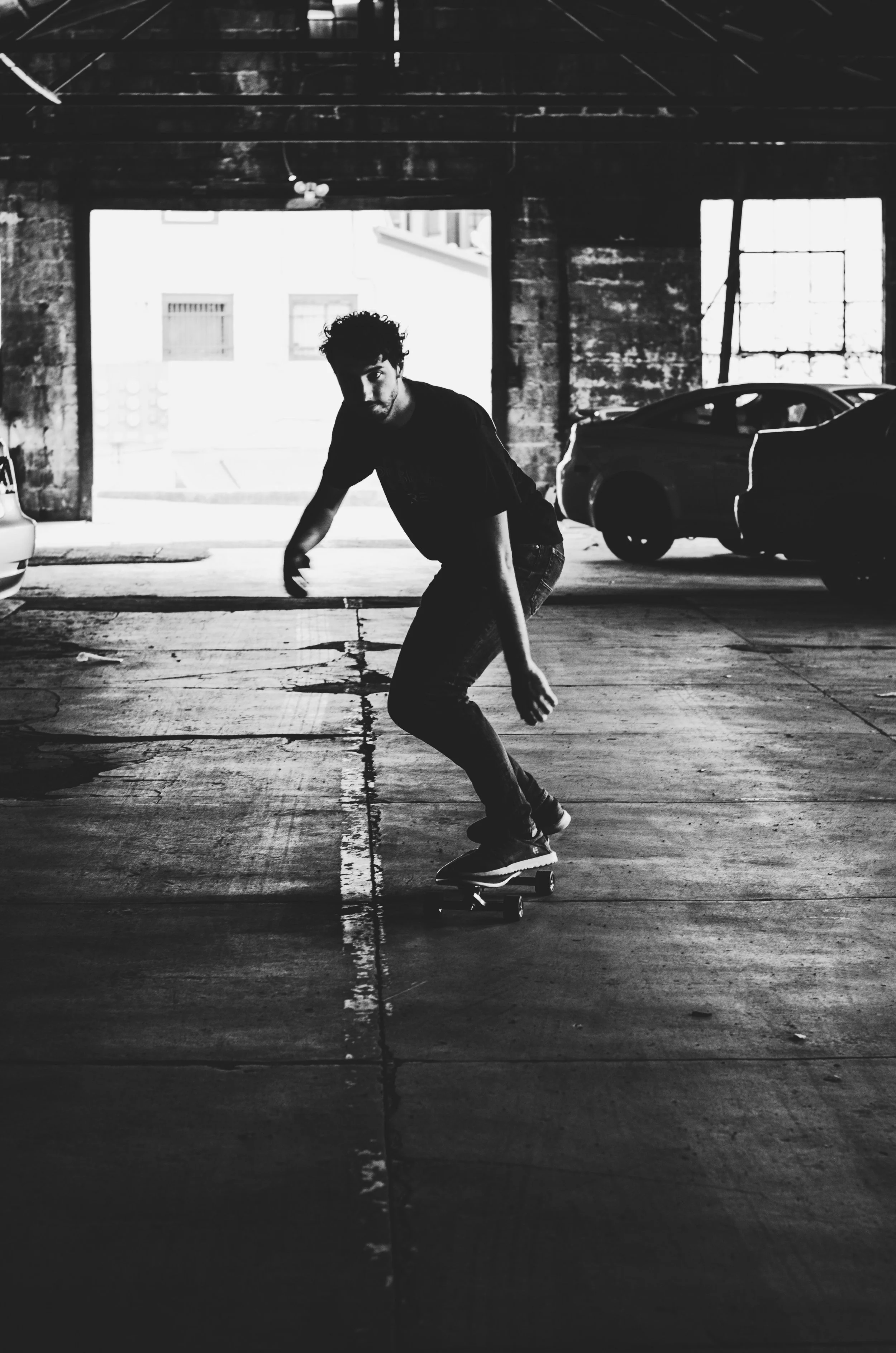Joven patinando en un garaje con luces de fondo y paredes de ladrillo expuesto.